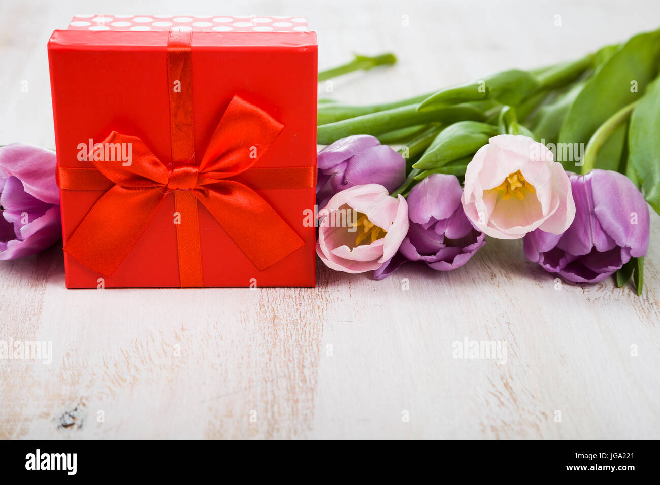 Bouquet de tulipes et un cadeau sur un fond de bois. encore la vie avec de belles fleurs en vacances. Banque D'Images