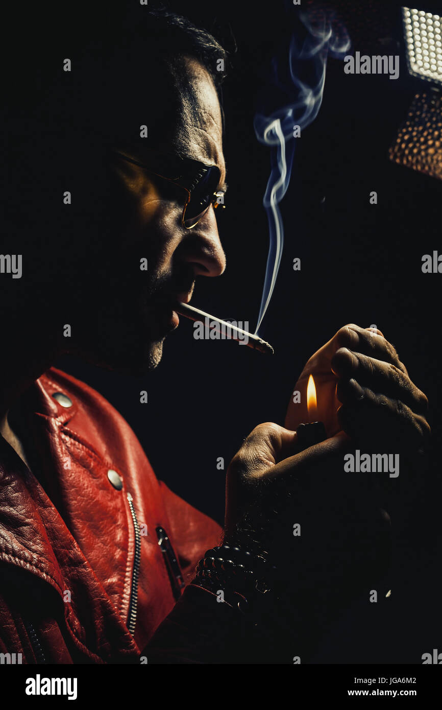 Dans l'homme adultes veste en cuir rouge, fumant un cigare. Banque D'Images