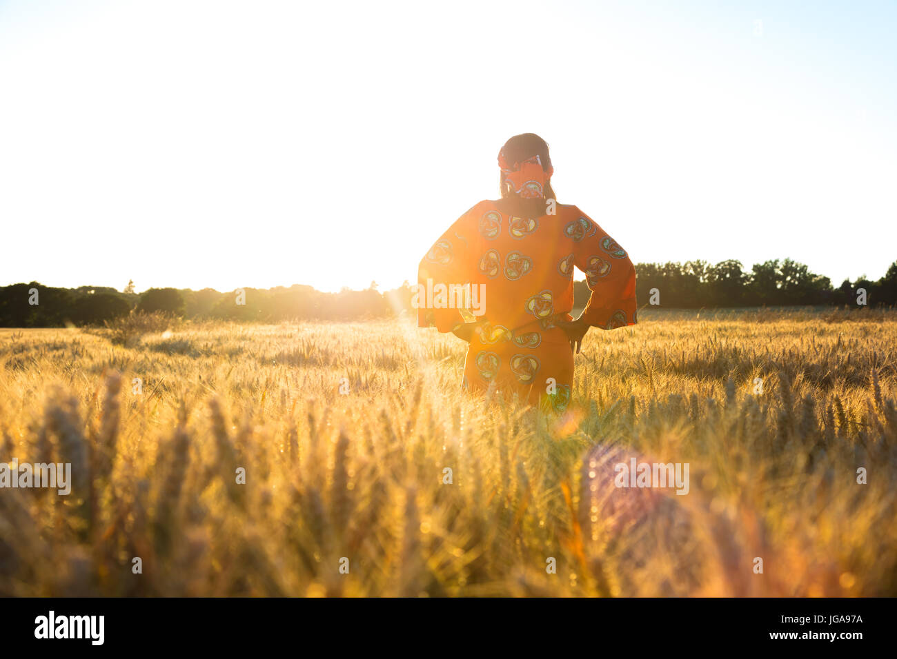 Femme africaine en vêtements traditionnels debout dans un champ d'orge ou les cultures de blé au coucher et au lever du soleil Banque D'Images