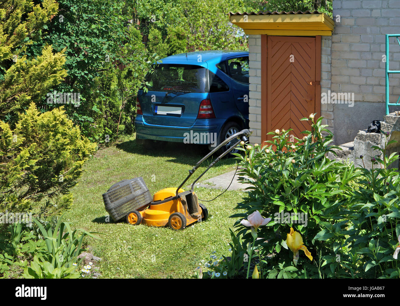 Vieux casse-électriques se trouvent sur la tondeuse jardin herbe verte. L'été ensoleillé paysage jour agricoles pauvres Banque D'Images