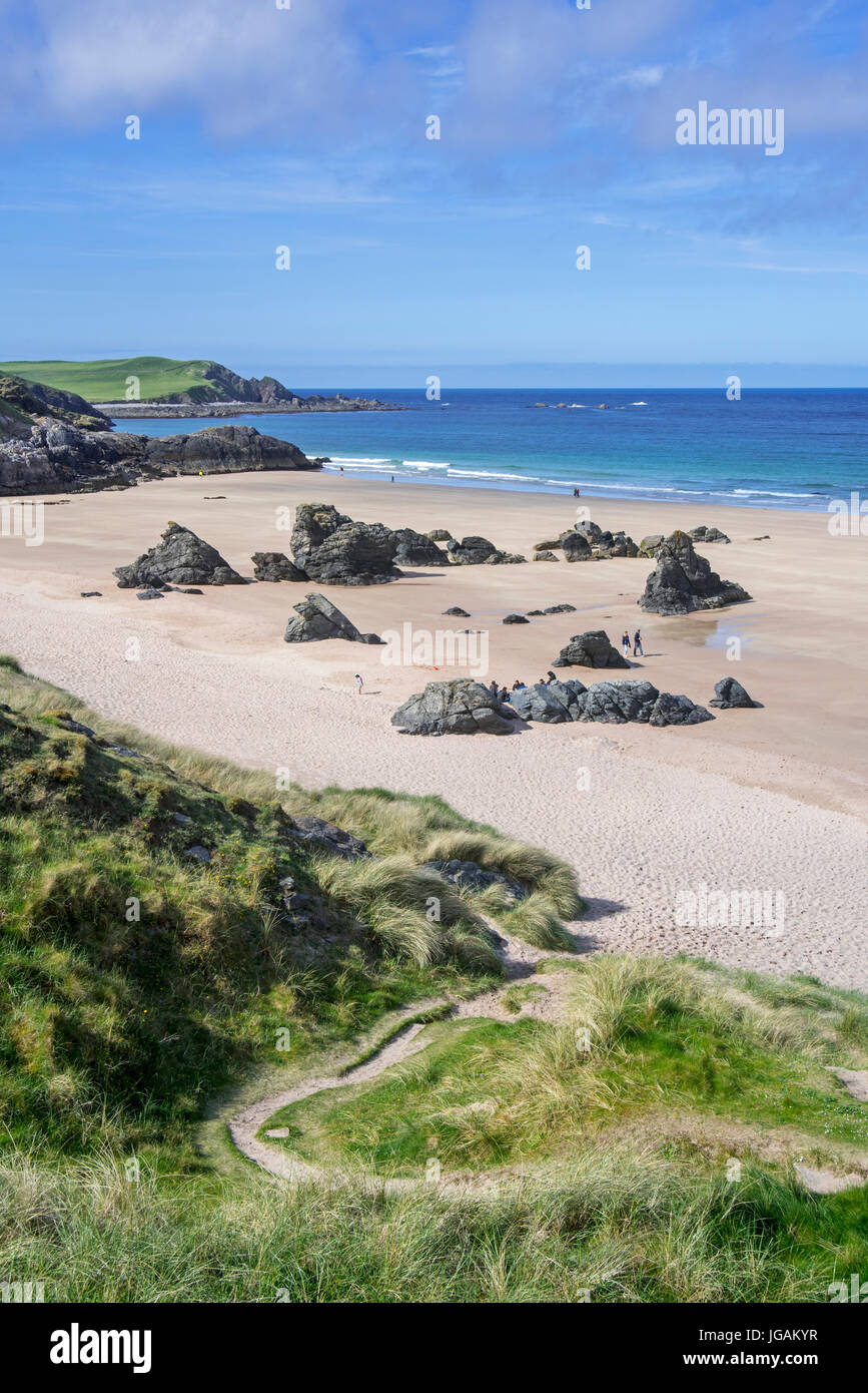 Les touristes marchant sur une plage de sable avec des rochers près de Durness, Sutherland, Highlands, Scotland, UK Banque D'Images