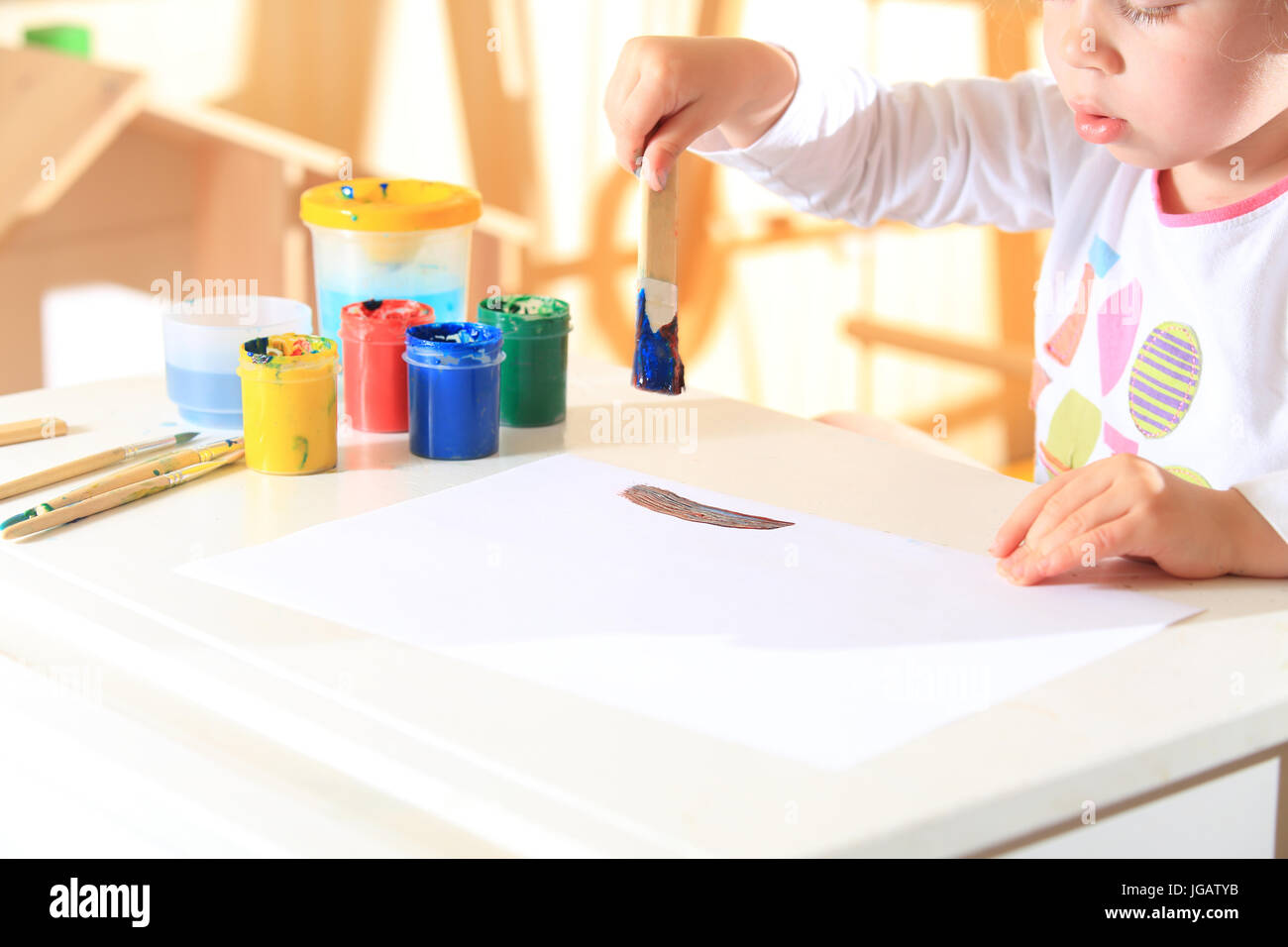 Enfant avec un pinceau dans la peinture s'inspire. Petite fille à l'aide de peinture pour l'art. Banque D'Images