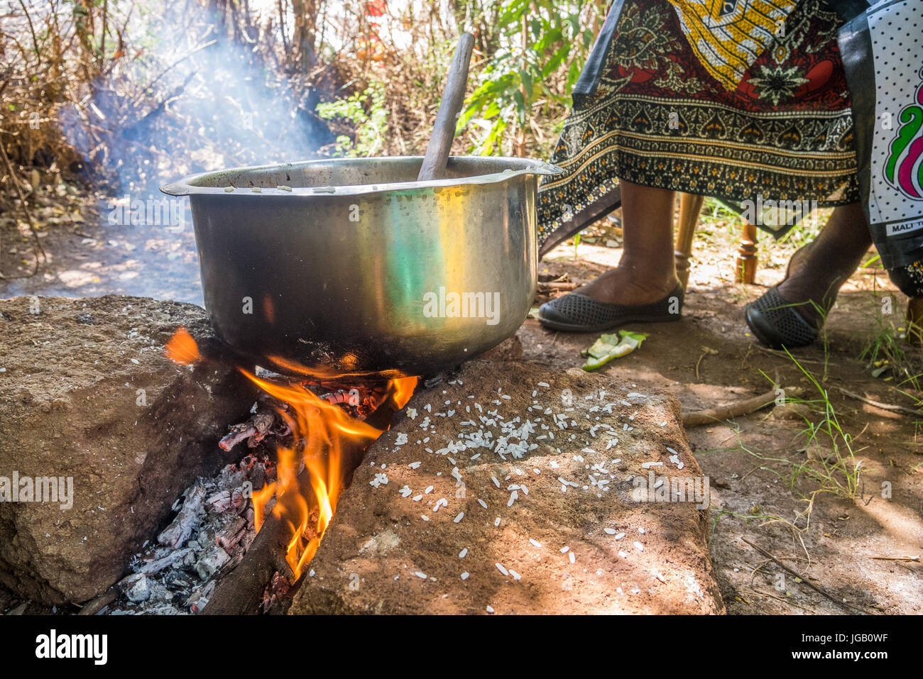 Femme africaine cuisiniers pilau dans bol en argent sur le feu Banque D'Images