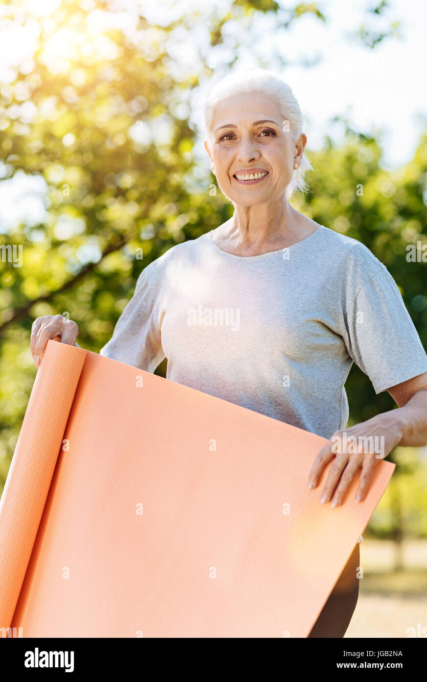 Ravis de Positive woman holding tapis de yoga Banque D'Images
