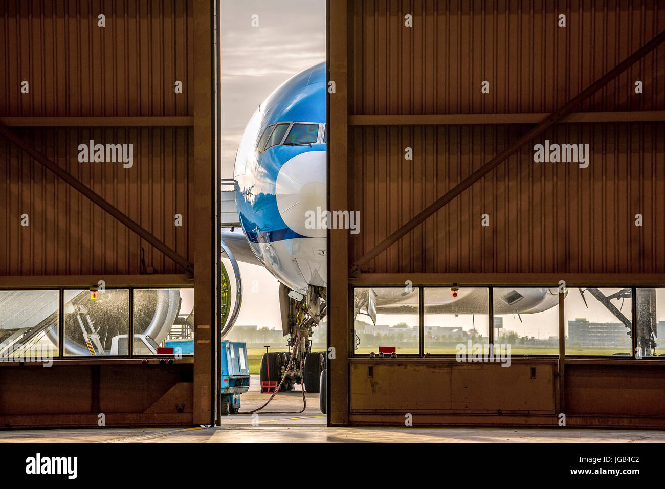 Avion Bleu en face de la moitié ouvert porte de hangar Banque D'Images