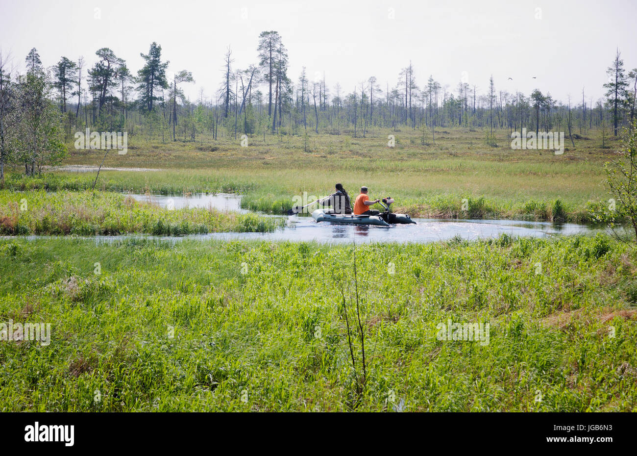Deux hommes dans un bateau gonflable flottant sur un méandre de la rivière marécageuse dans la toundra sibérienne Banque D'Images