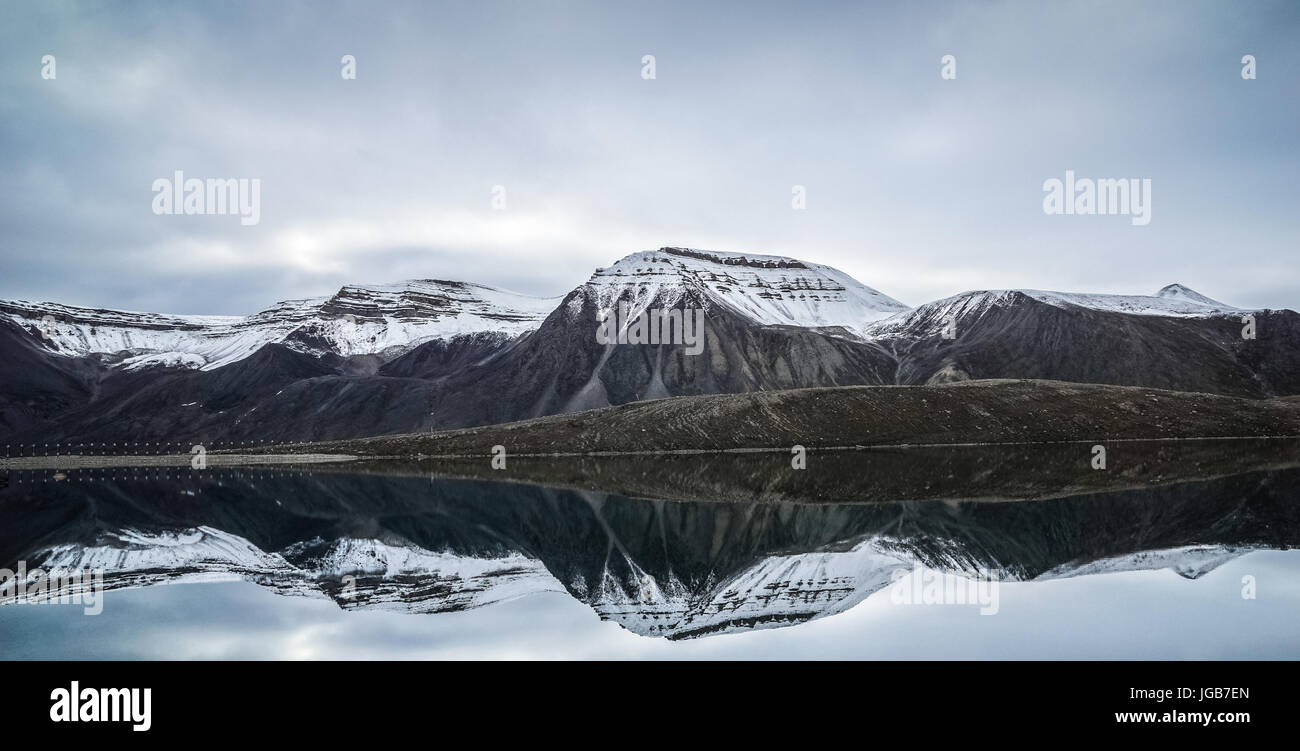 Les montagnes en miroir dans l'eau potable de la ville russe de Pyramiden Svalbard. Banque D'Images
