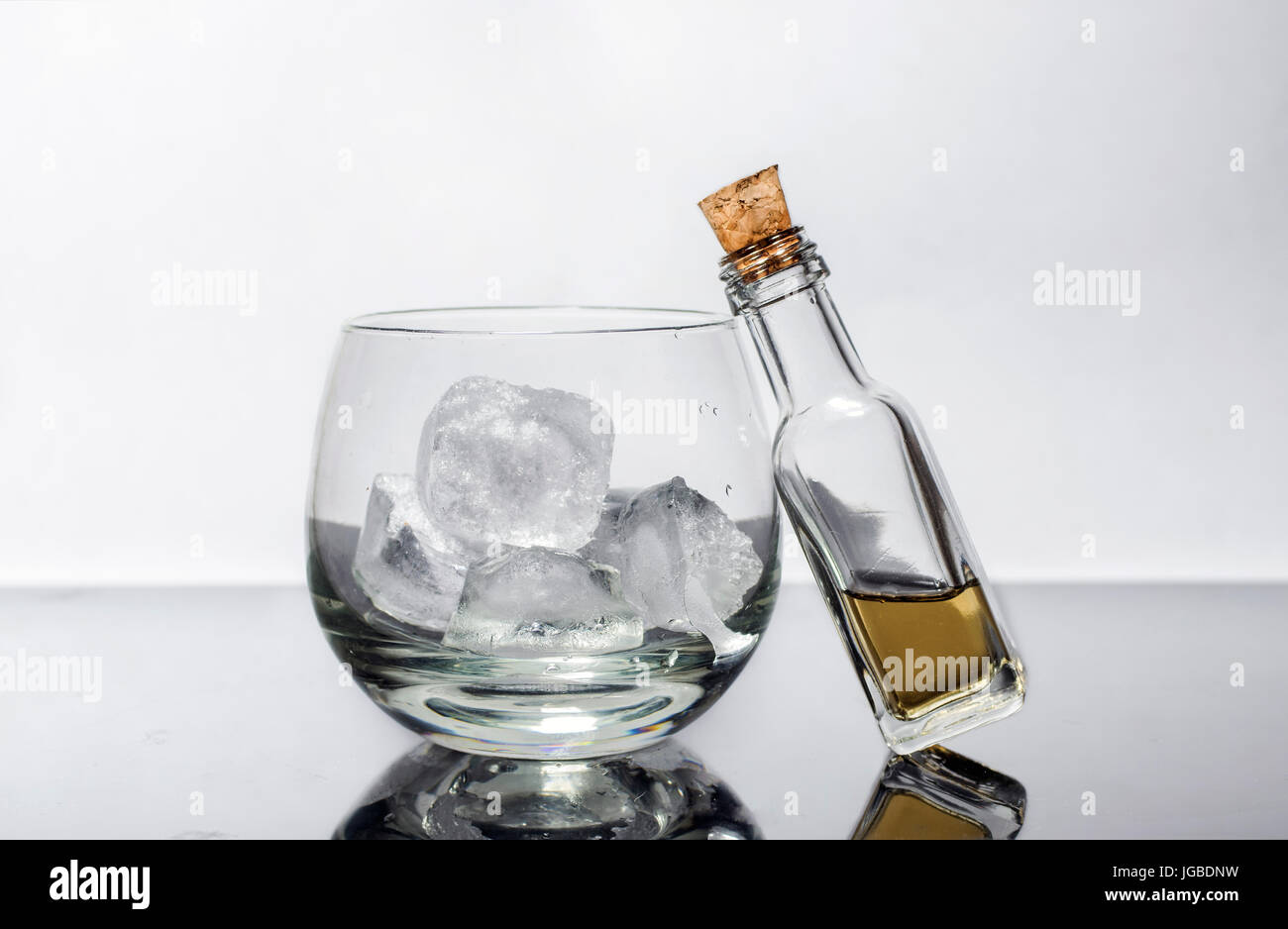 Petite bouteille de whisky bouchonnée miniature et un verre de whisky avec de la glace Banque D'Images