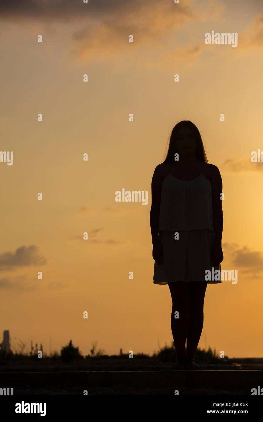 Silhouette of a woman standing outdoors at sunset Banque D'Images