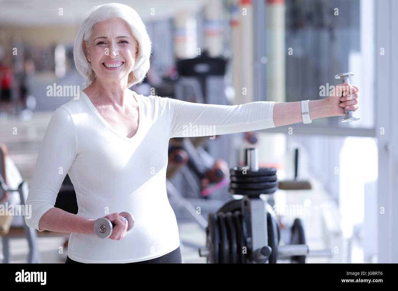 Smiling old lady l'entraînement avec haltères courtes Banque D'Images