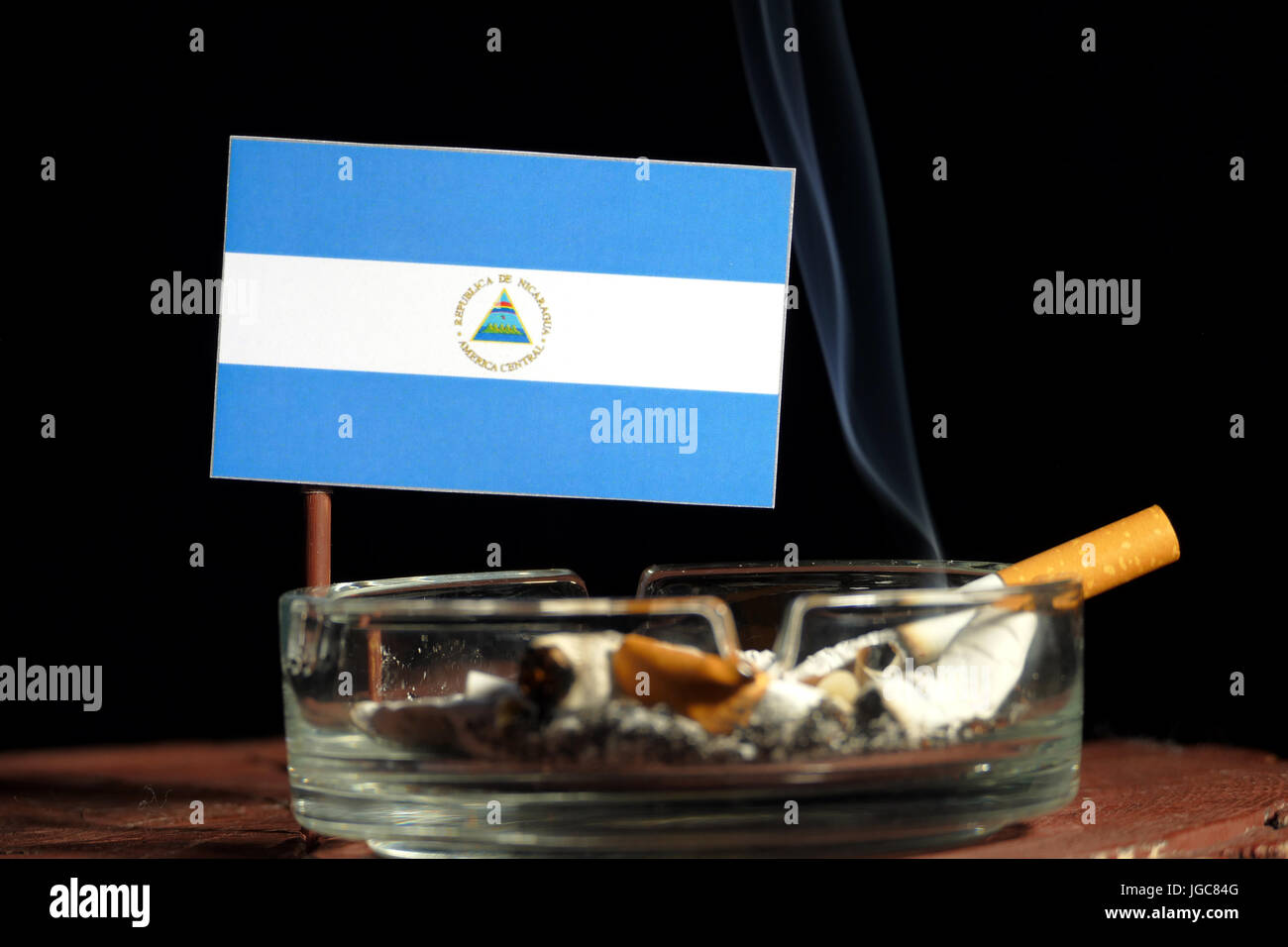 Drapeau du Nicaragua avec la cigarette dans le cendrier isolé sur fond noir Banque D'Images