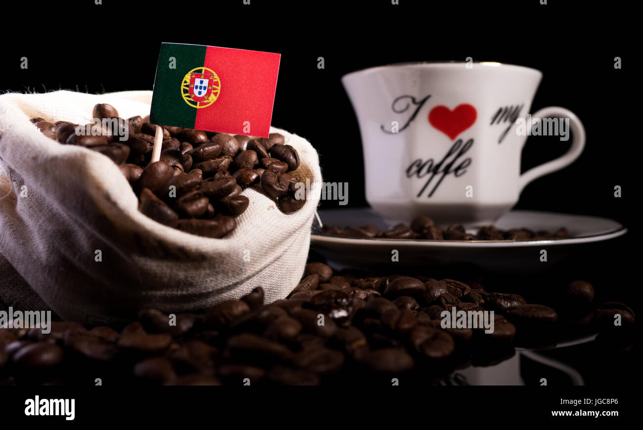 Drapeau portugais dans un sac avec les grains de café isolé sur fond noir Banque D'Images
