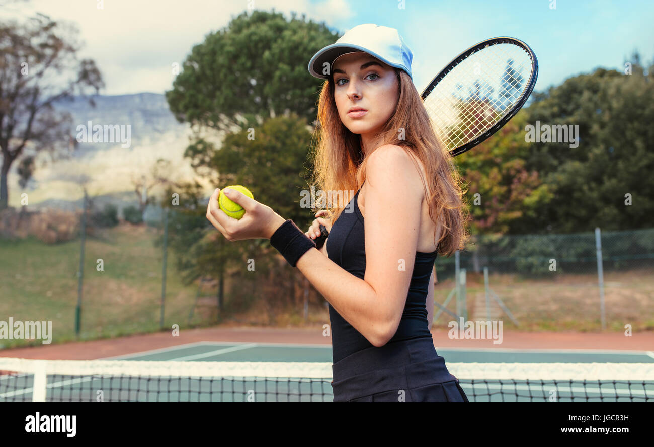 Portrait de belle jeune sportive avec raquette et balle sur le court de tennis. joueurs de tennis s'entraînant sur le court. Banque D'Images