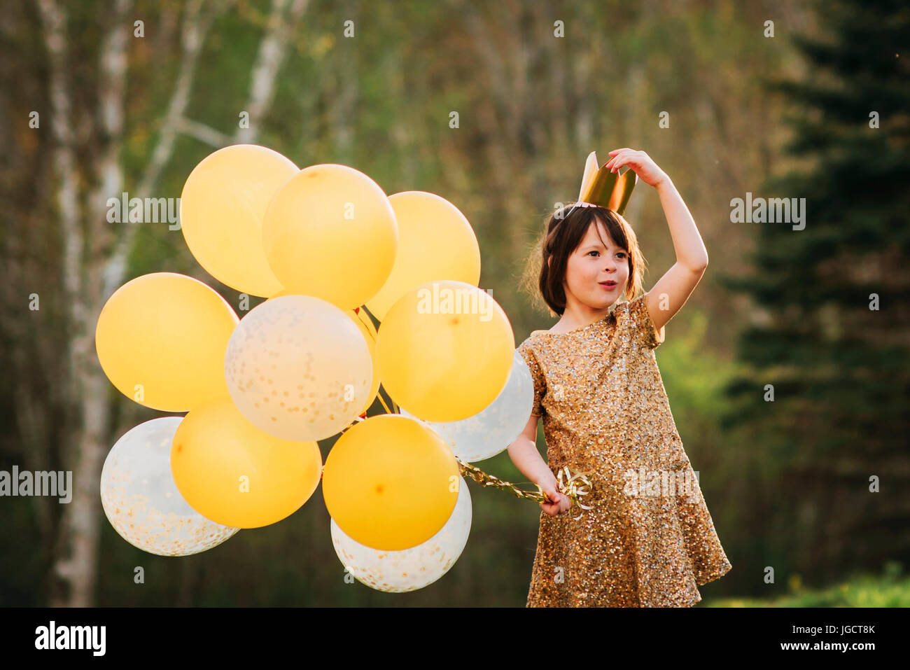 Jeune fille dans une robe d'or portant une couronne portant des ballons Banque D'Images