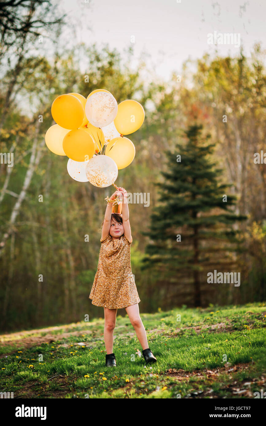 Jeune fille dans une robe d'or portant une couronne portant des ballons Banque D'Images