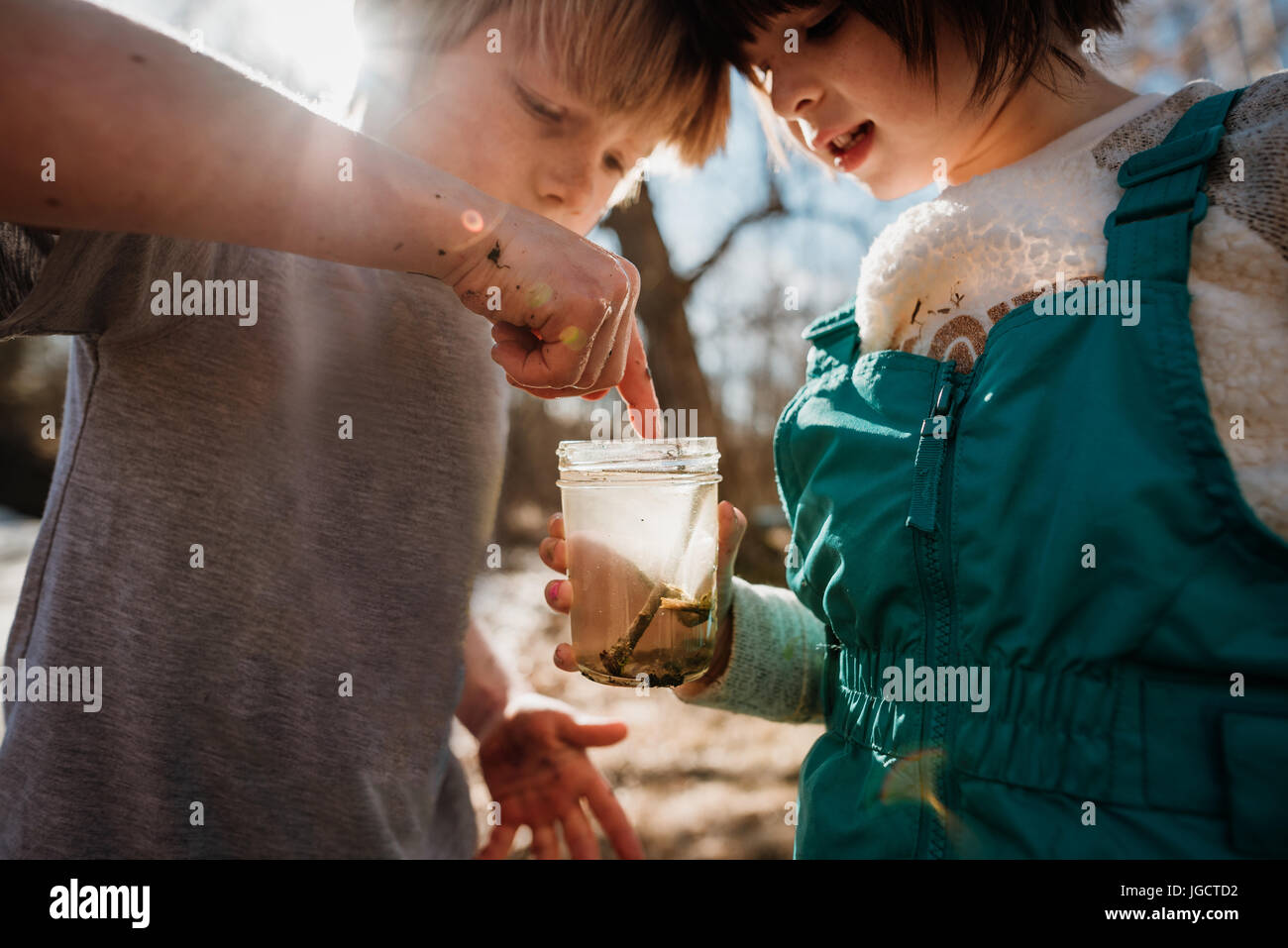 Garçon et fille tenant un pot avec de l'eau bugs Banque D'Images