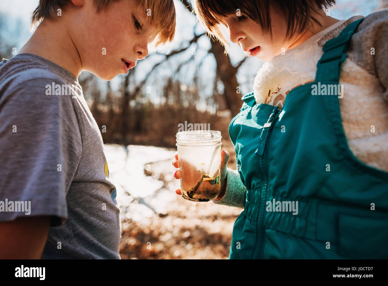 Garçon et fille tenant un pot avec de l'eau bugs Banque D'Images