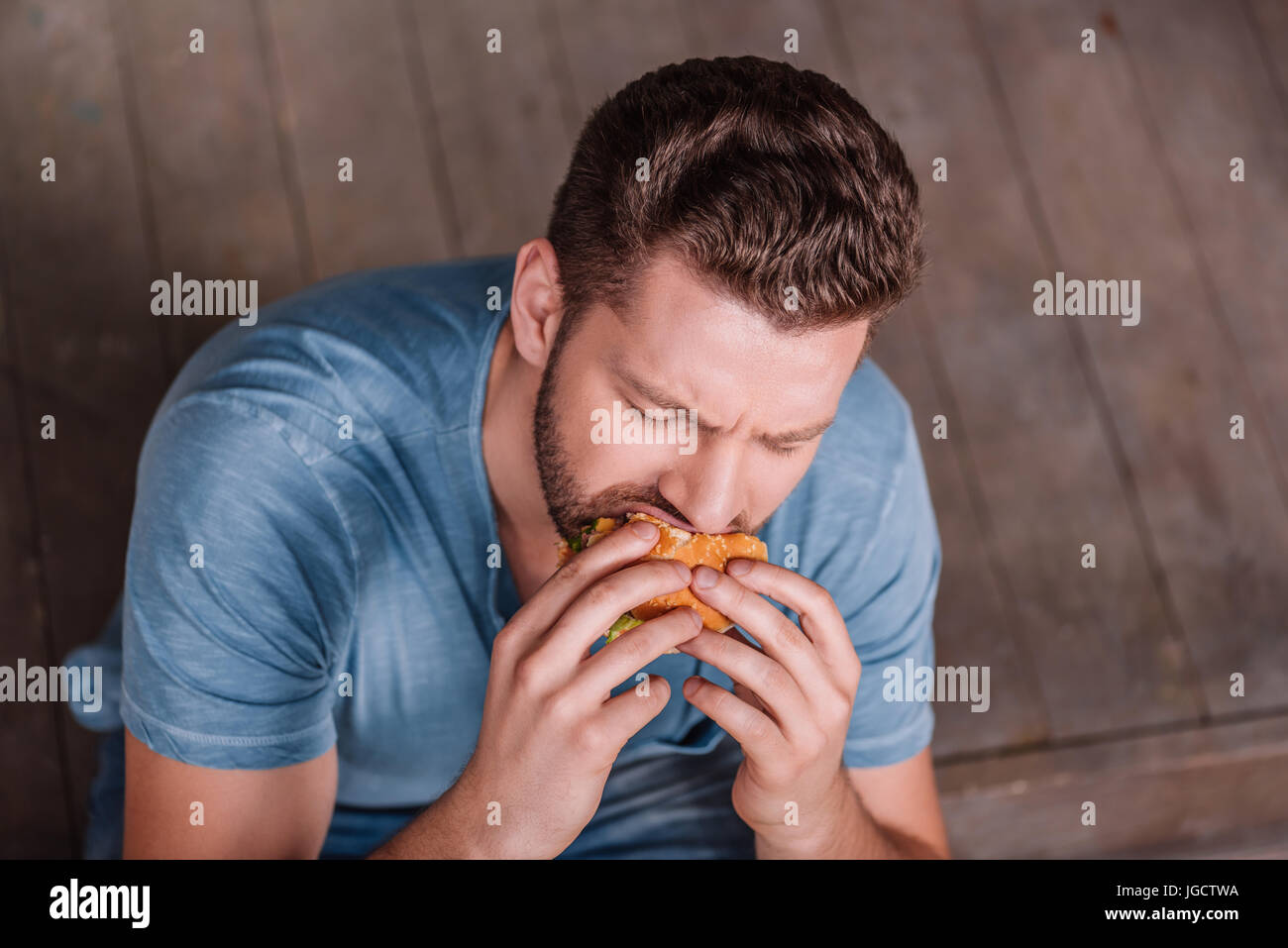 High angle view of young man eating hamburger Banque D'Images