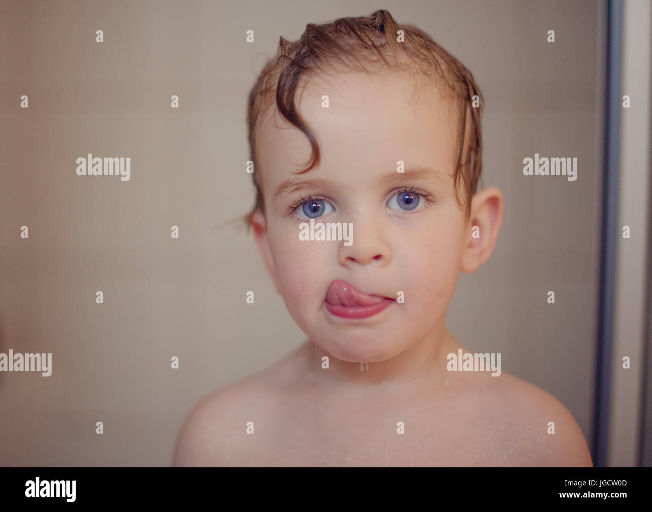 Portrait d'un garçon dans la douche lécher ses lèvres Banque D'Images