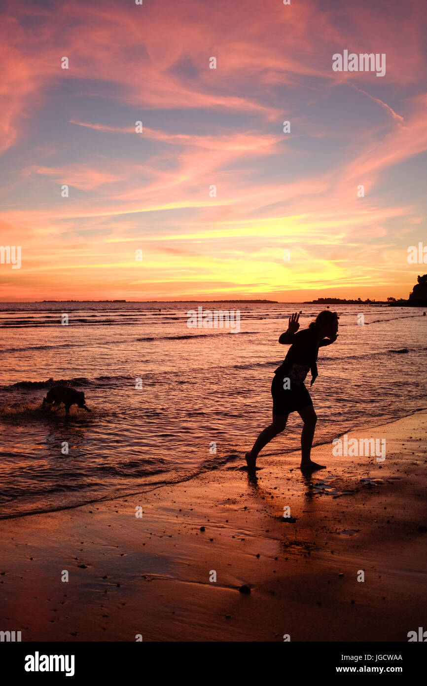 Silhouette d'une jeune femme et son chien hors de la mer, Fouras, Nouvelle-Aquitaine, France Banque D'Images