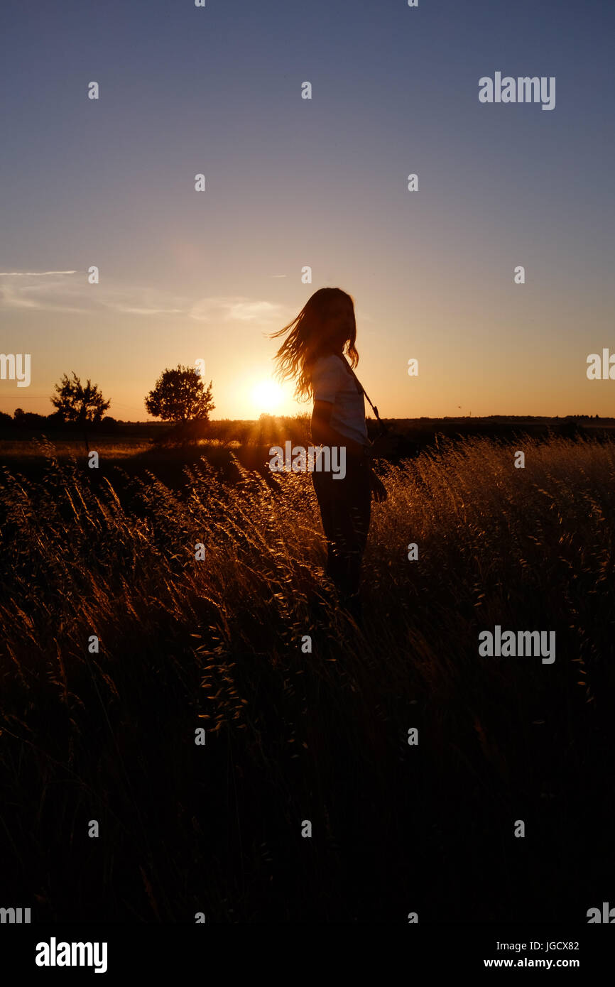 Silhouette d'une jeune fille debout dans un champ au coucher du soleil, Niort, France Banque D'Images