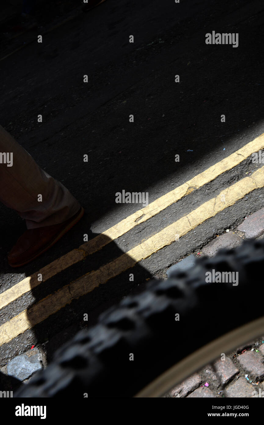 Le pied de l''homme sur route, après les lignes jaunes et double roue de bicyclette casting shadow Banque D'Images