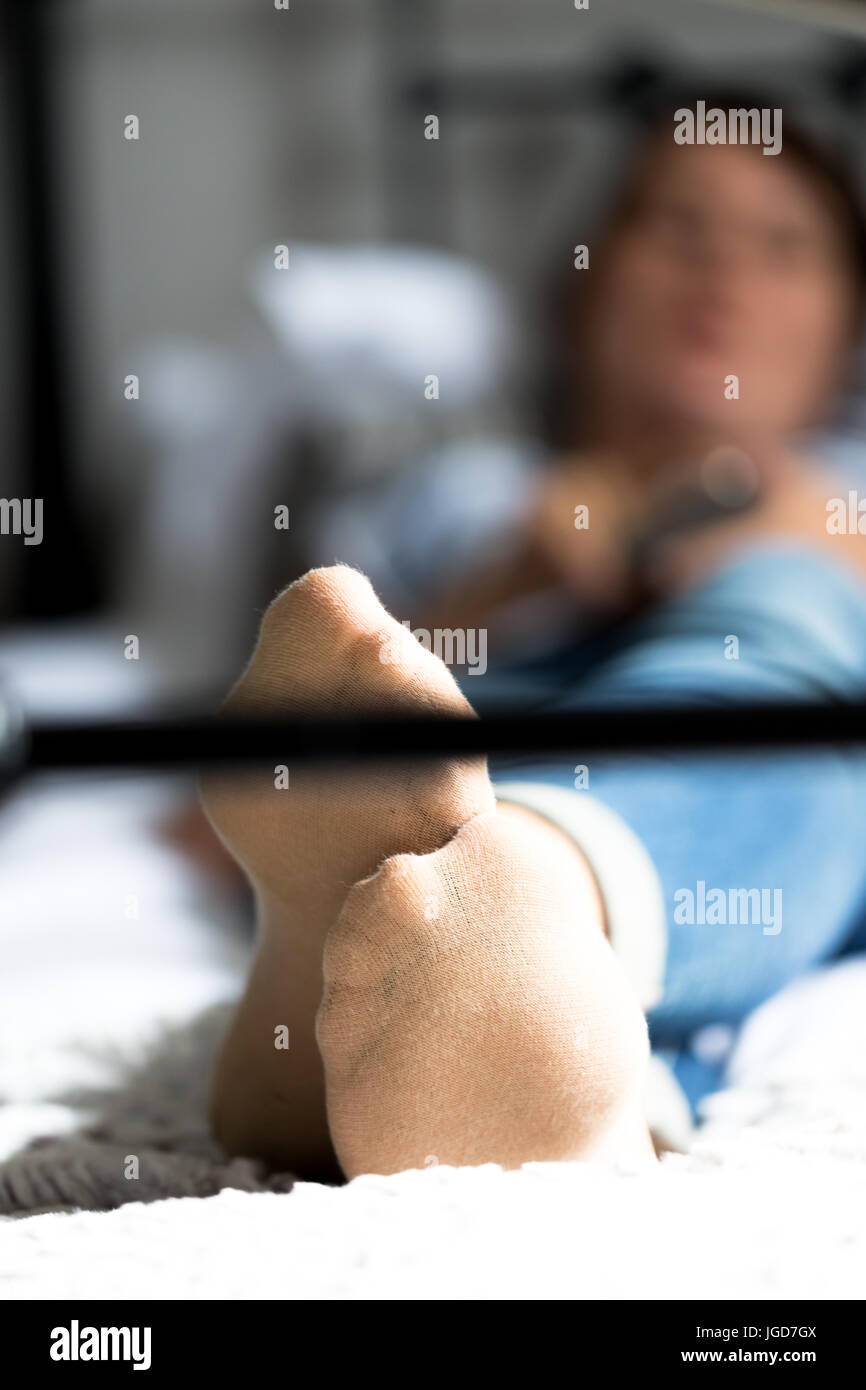 Les jeunes femmes adultes, dans son fourtys, couchée sur un lit de style vintage à fenêtre lumineuse. Se concentrer sur les pieds. Culture verticale, faible profondeur de champ. Banque D'Images