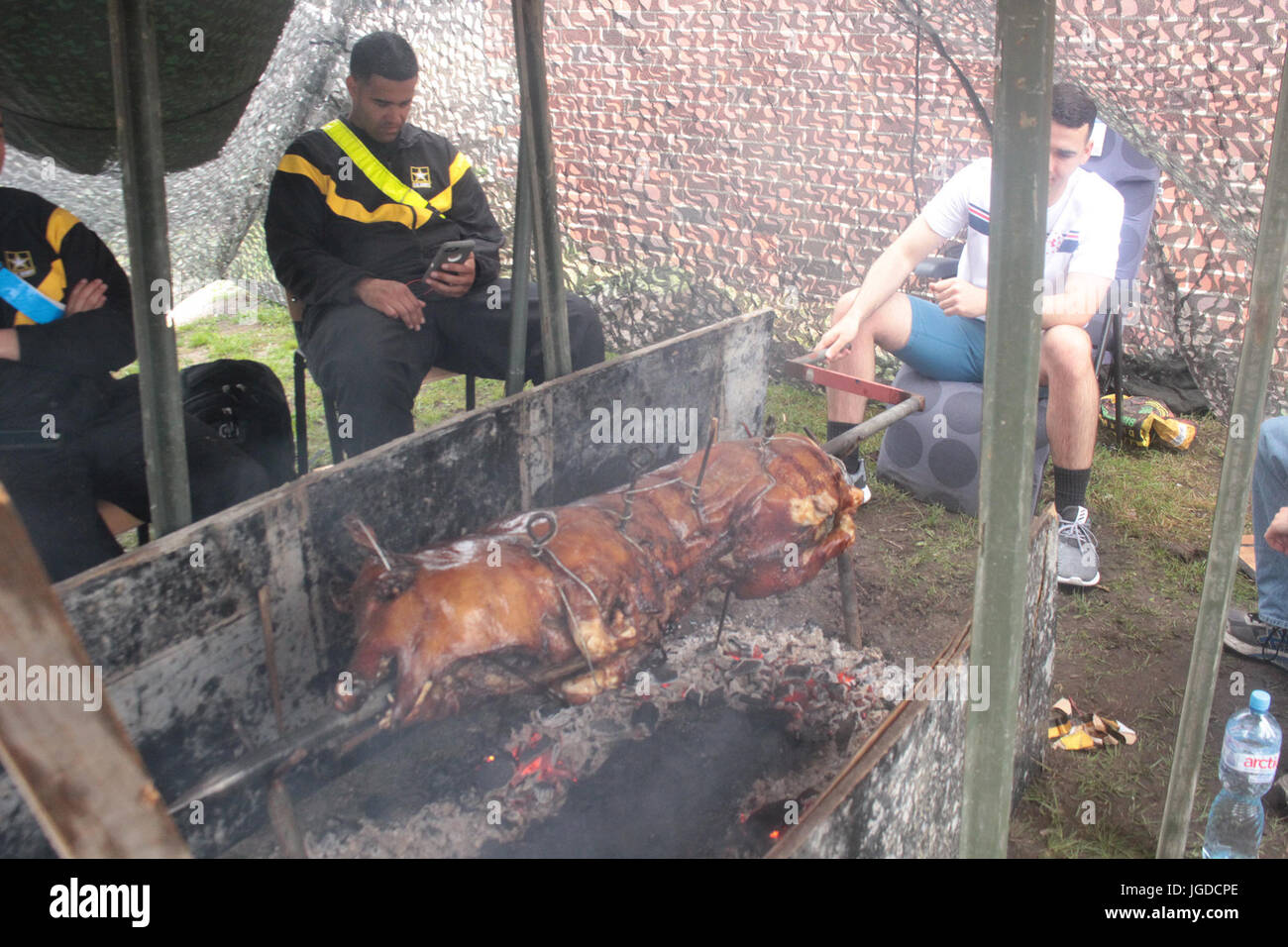 Pologne Groupe de combat des soldats américains un porc rôti en préparation pour le groupement tactique du premier jour de l'indépendance Fête nationale à Bemowo Piskie Zone de formation le 4 juillet. Cette année, la maison de vacances a tenu une signification particulière pour la bataille des soldats américains du groupe qu'ils ont pu partager un jour de l'indépendance traditionnelle célébration avec leurs partenaires roumains et britanniques stationnés avec eux en Pologne. (U.S. Photo par le Sgt armée Jimmy Golden/libérés) Banque D'Images