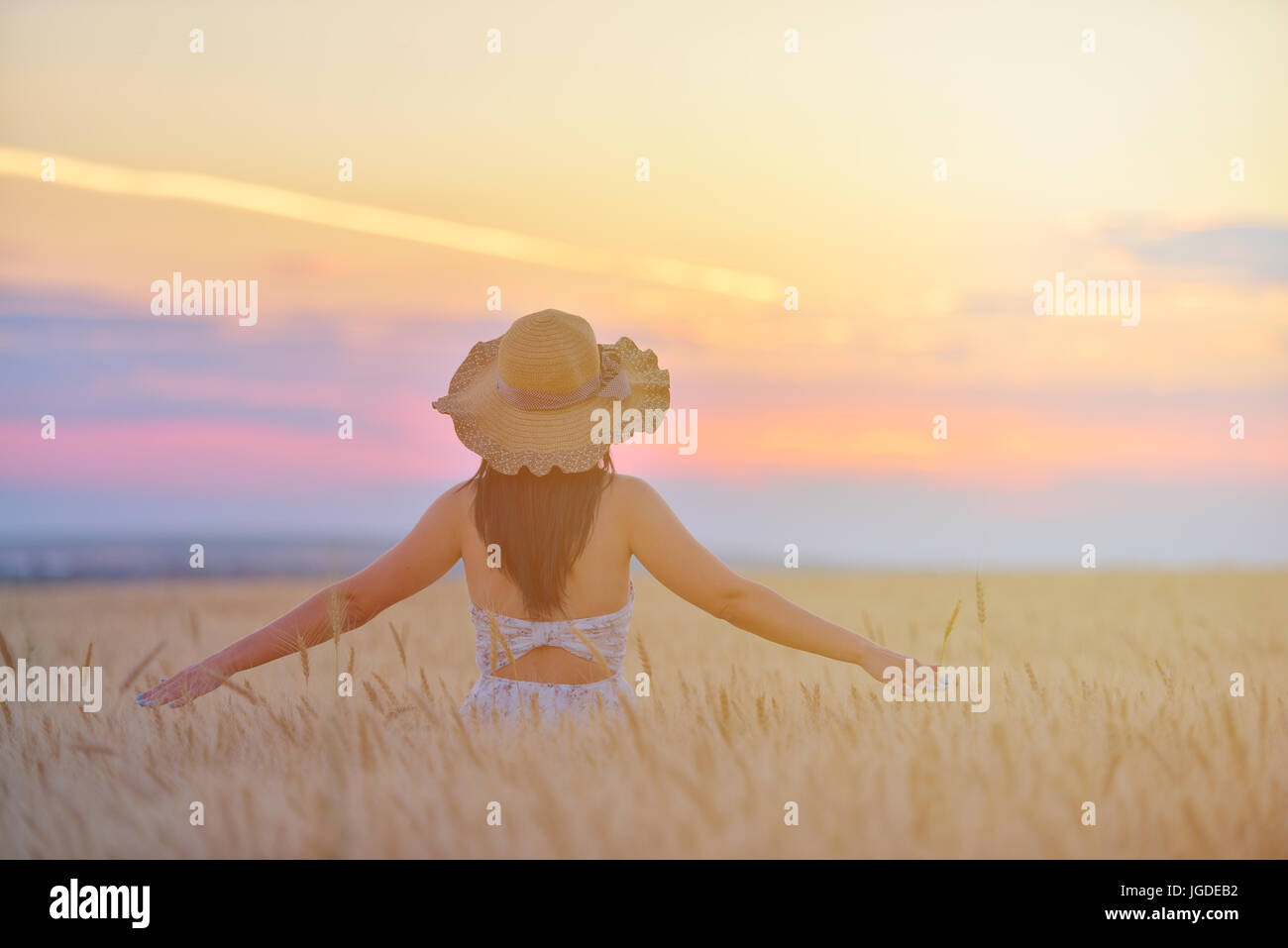 Closeup portrait of smiling young woman dans la nature. cheerful young Beautiful woman touching wheat field at sunset Banque D'Images