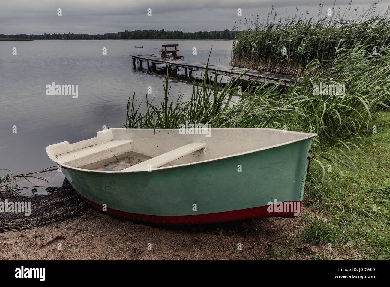 Bateau de pêcheur et le pont en arrière-plan. Soir de pluie à la Mazurie Lake d'Inulec, Pologne Banque D'Images