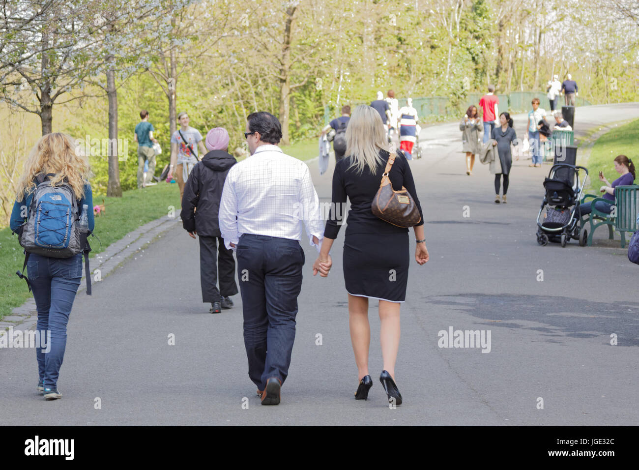 Le parc Kelvingrove scène ensoleillée people walking couple main dans la main yeux ailleurs Banque D'Images