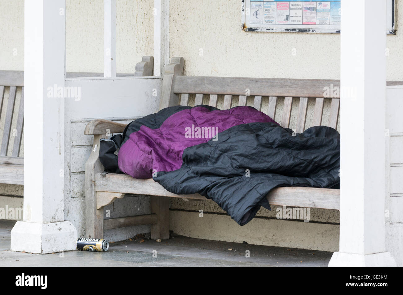 La rue dans la rue. Personne sans-abri dormant sur un banc dans le Royaume-Uni. Banque D'Images