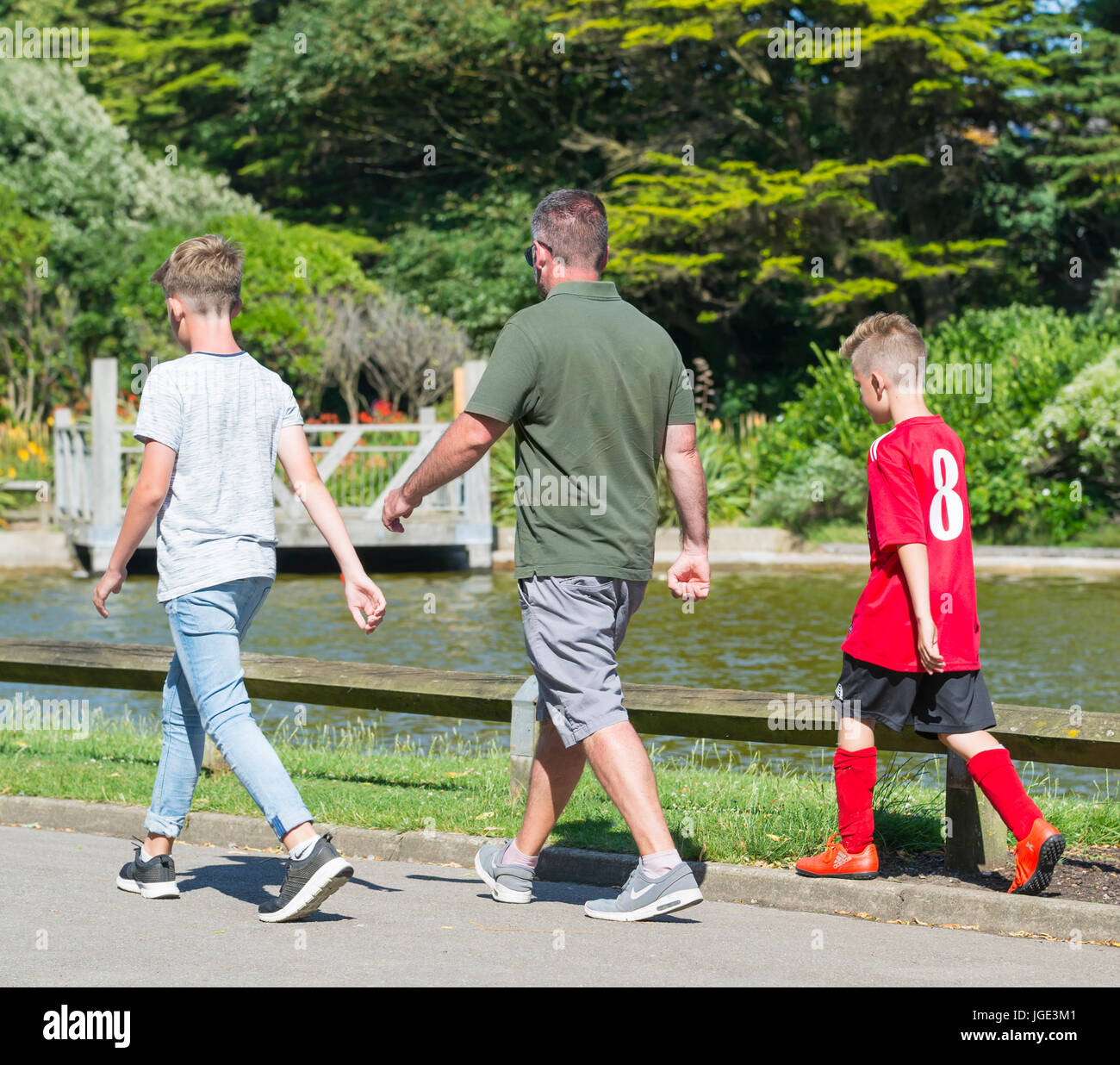 Père et fils à marcher ensemble dans un parc sur une chaude journée d'été. Banque D'Images