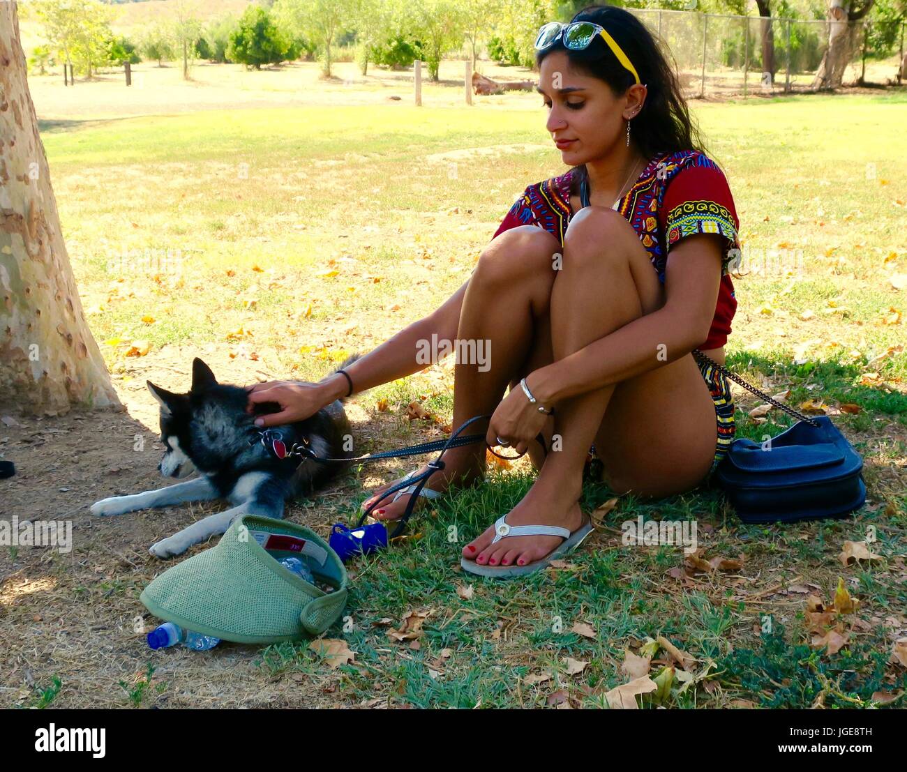 Jolie femme habillée de couleurs vives avec chien dans un parc Banque D'Images
