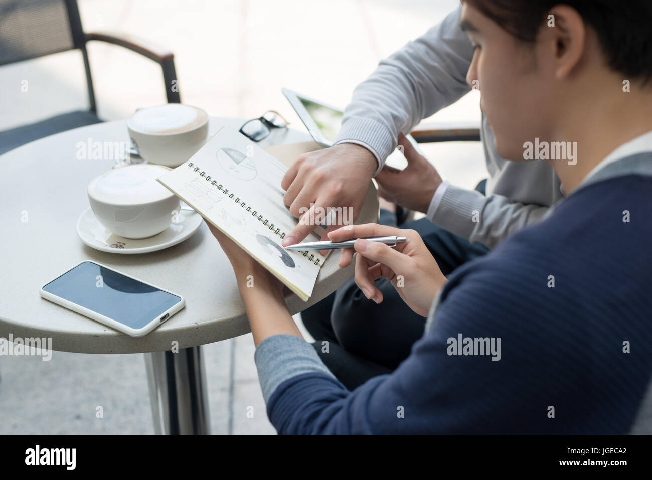 Deux jeunes hommes d'affaires dans les tenues de beau sourire, discuter dans un café. Banque D'Images