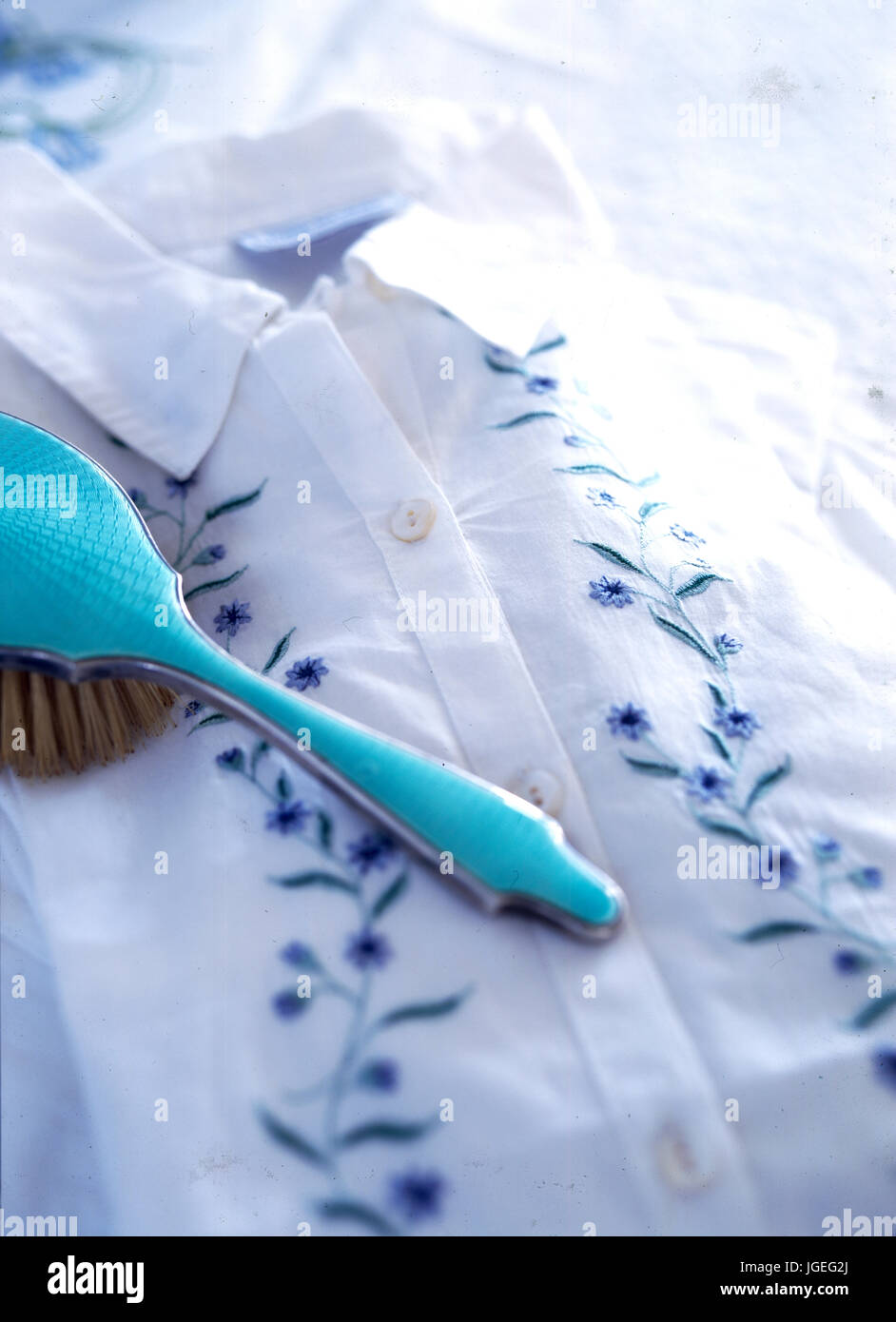 Libre d'émail turquoise vintage adossés sur brosse à cheveux bleu brodé et chemisier blanc Banque D'Images