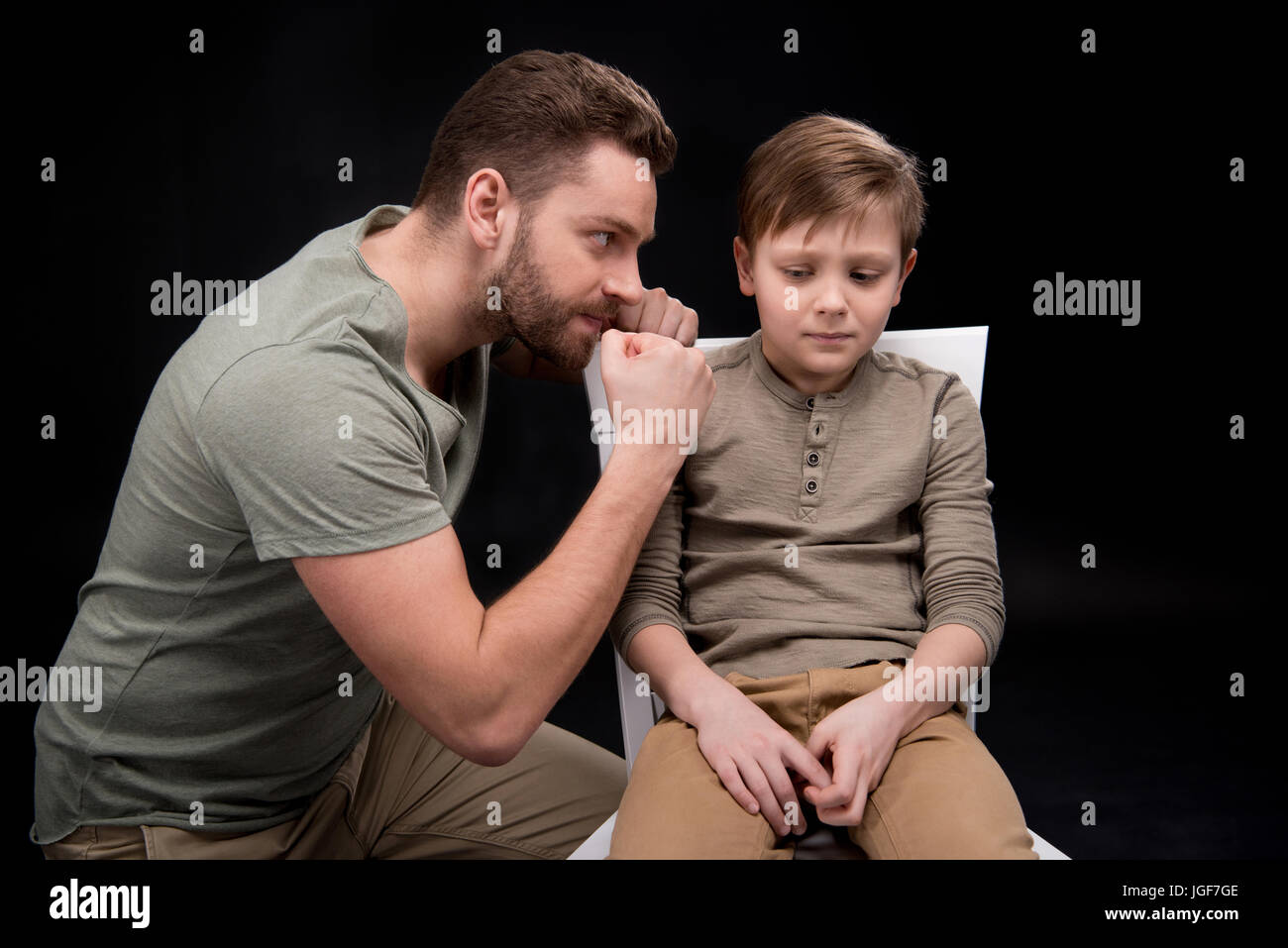 Père en colère menaçante et gesticulant de peur petit fils assis sur une chaise, les problèmes de famille concept Banque D'Images