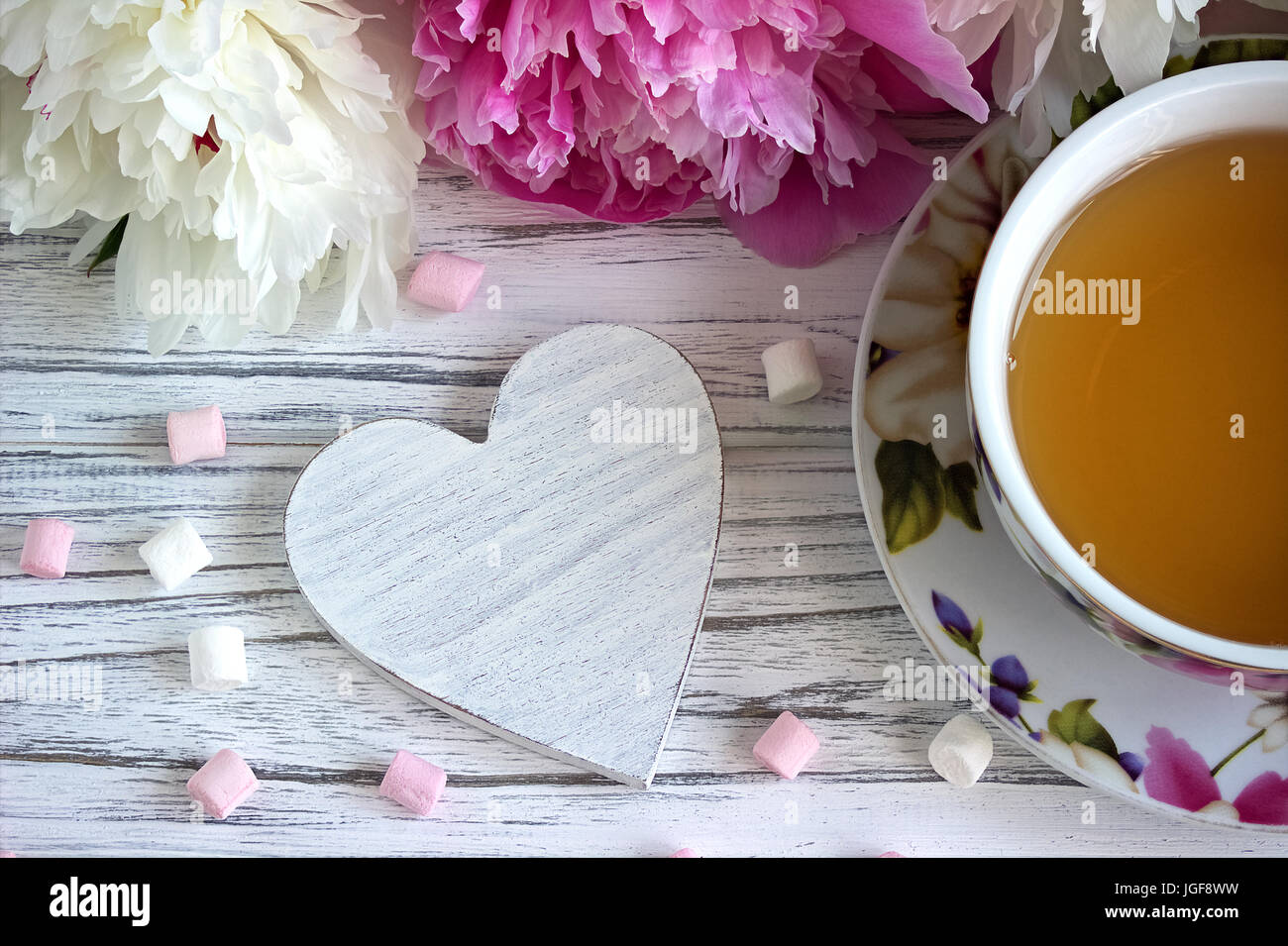 Fleurs de pivoines tasse de thé rose guimauve coeurs en rotin blanc sur un fond de bois - image Banque D'Images