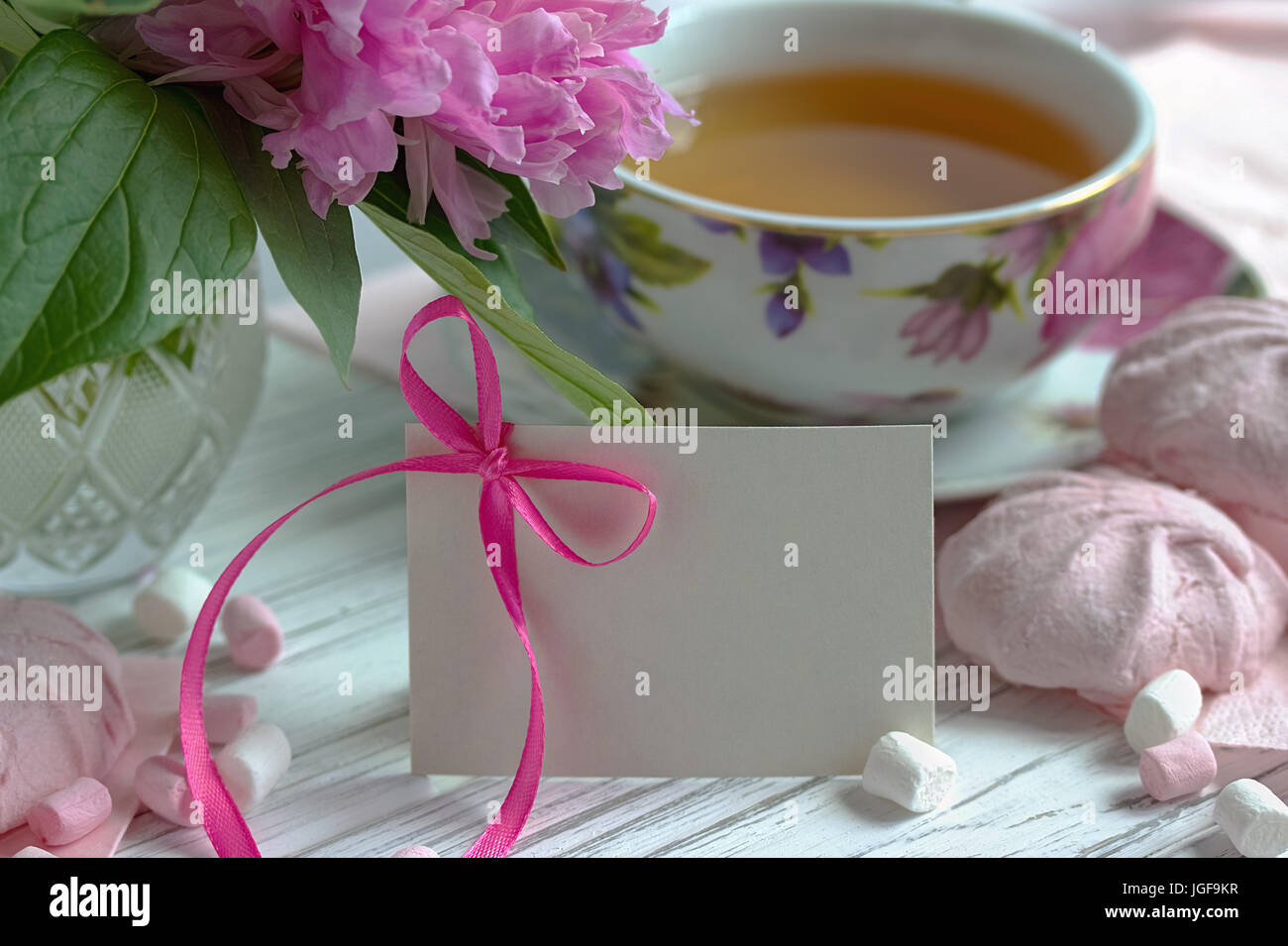 Les Pivoines rose fleurs tasse de thé carte de souhaits marshmallow sur un fond en bois blanc - stock image Banque D'Images