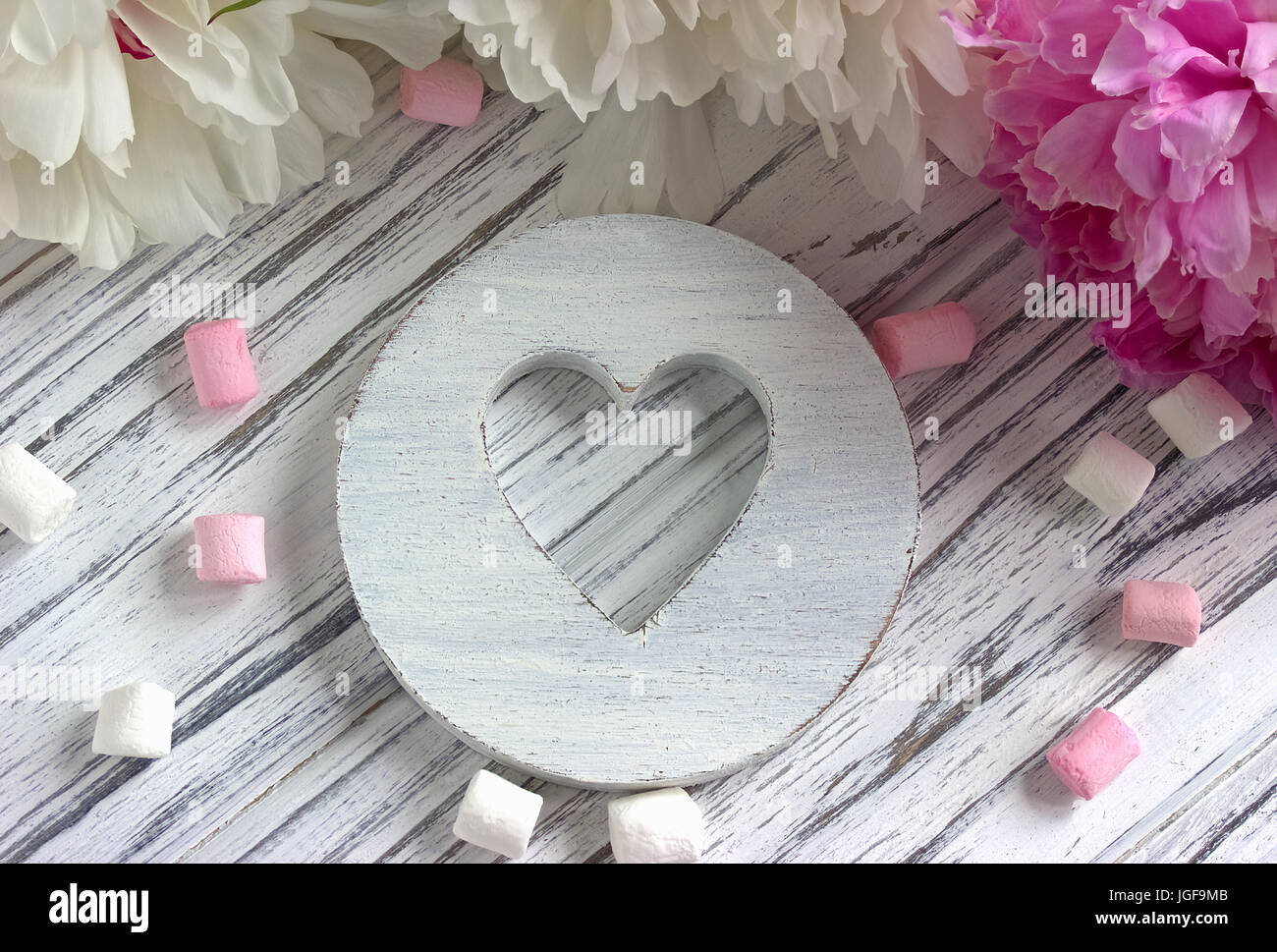 Fleurs de pivoines rose avec coeur en bois blanc de la guimauve sur un fond en bois blanc - stock image Banque D'Images