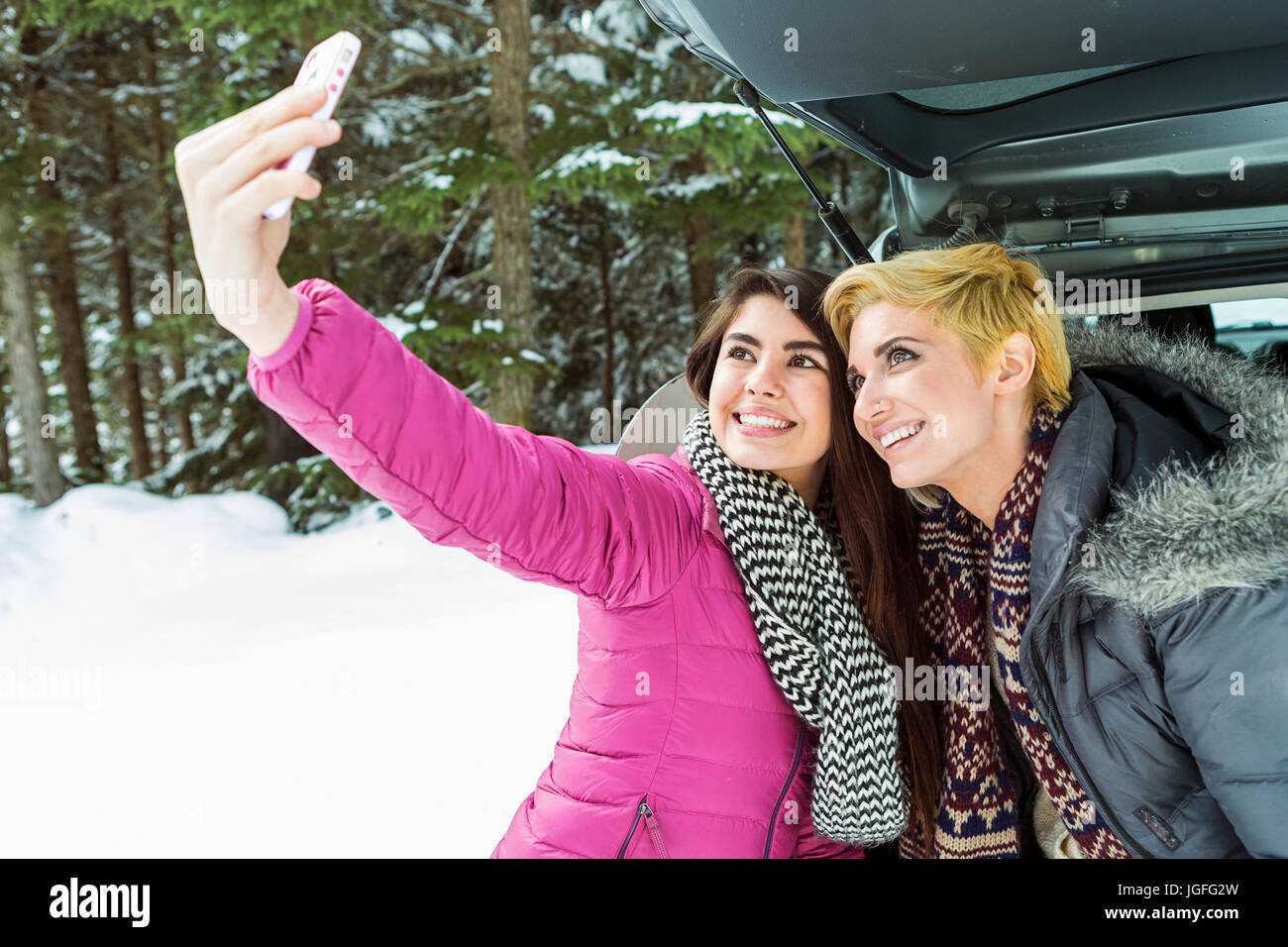 Les femmes chez car posant pour téléphone cellulaire en hiver selfies Banque D'Images
