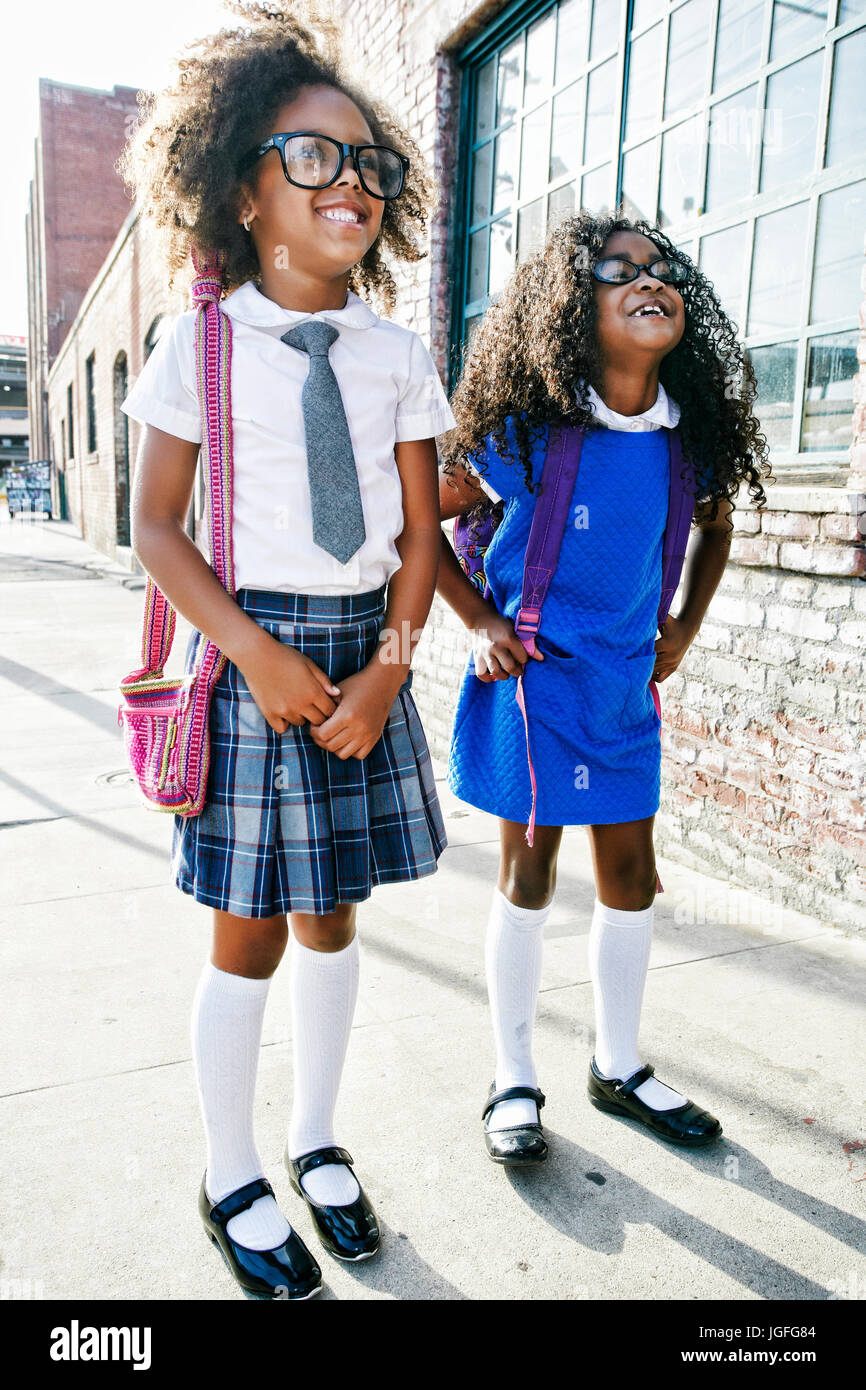 Smiling girls standing on sidewalk prêts pour l'école Banque D'Images