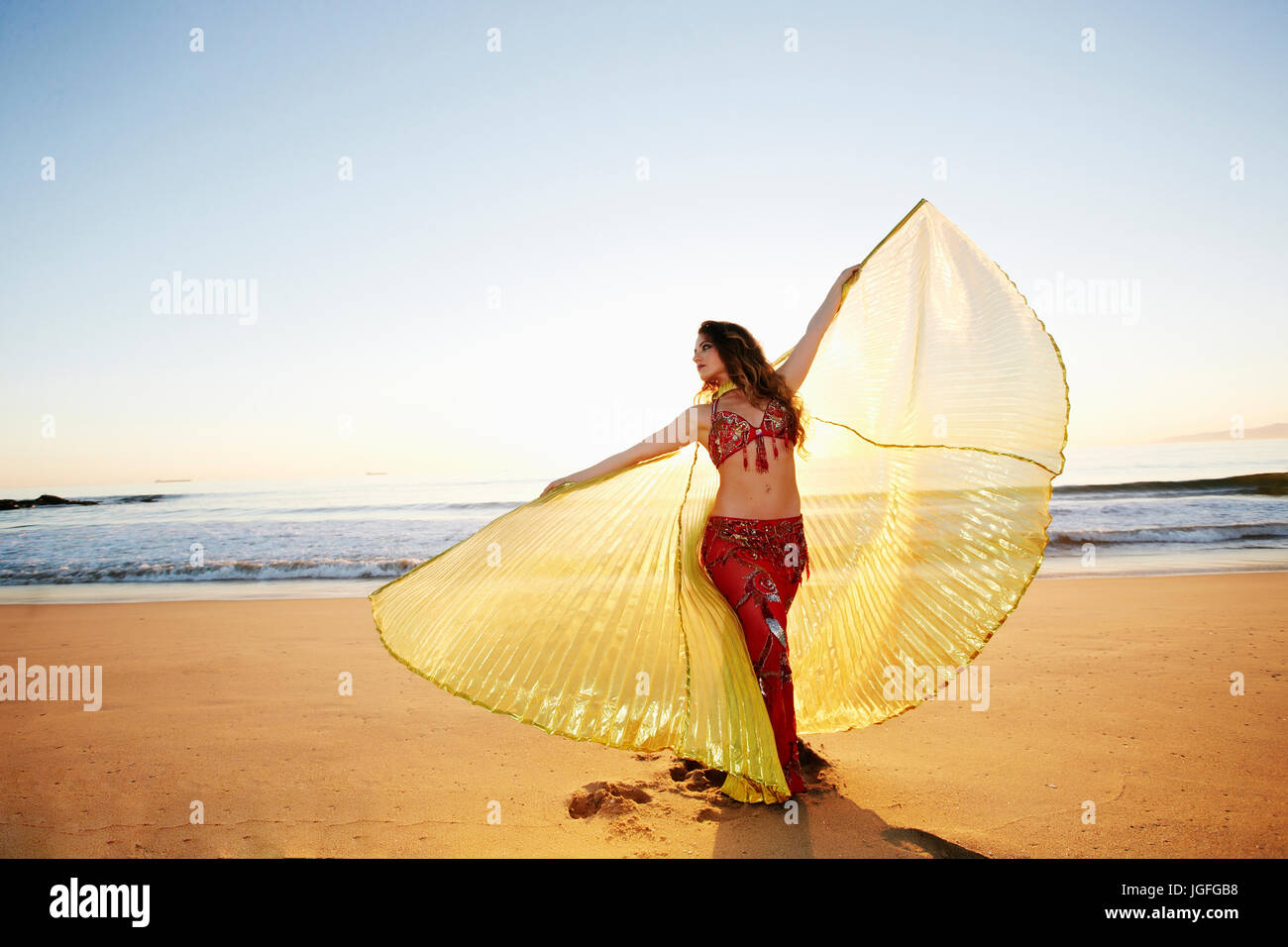 Woman holding belly dancer cape on beach Banque D'Images