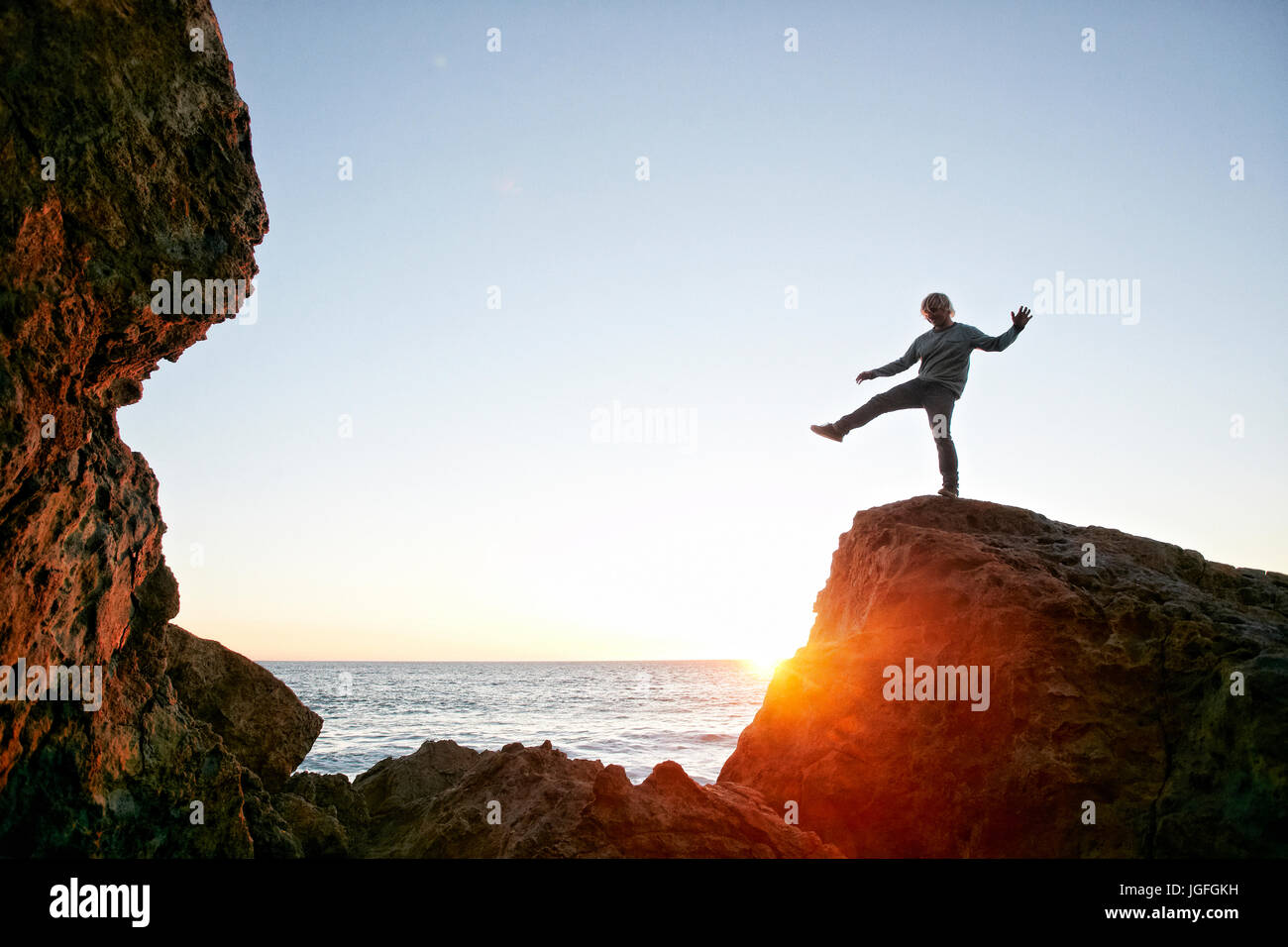 Caucasian man balancing on rock at Ocean Banque D'Images