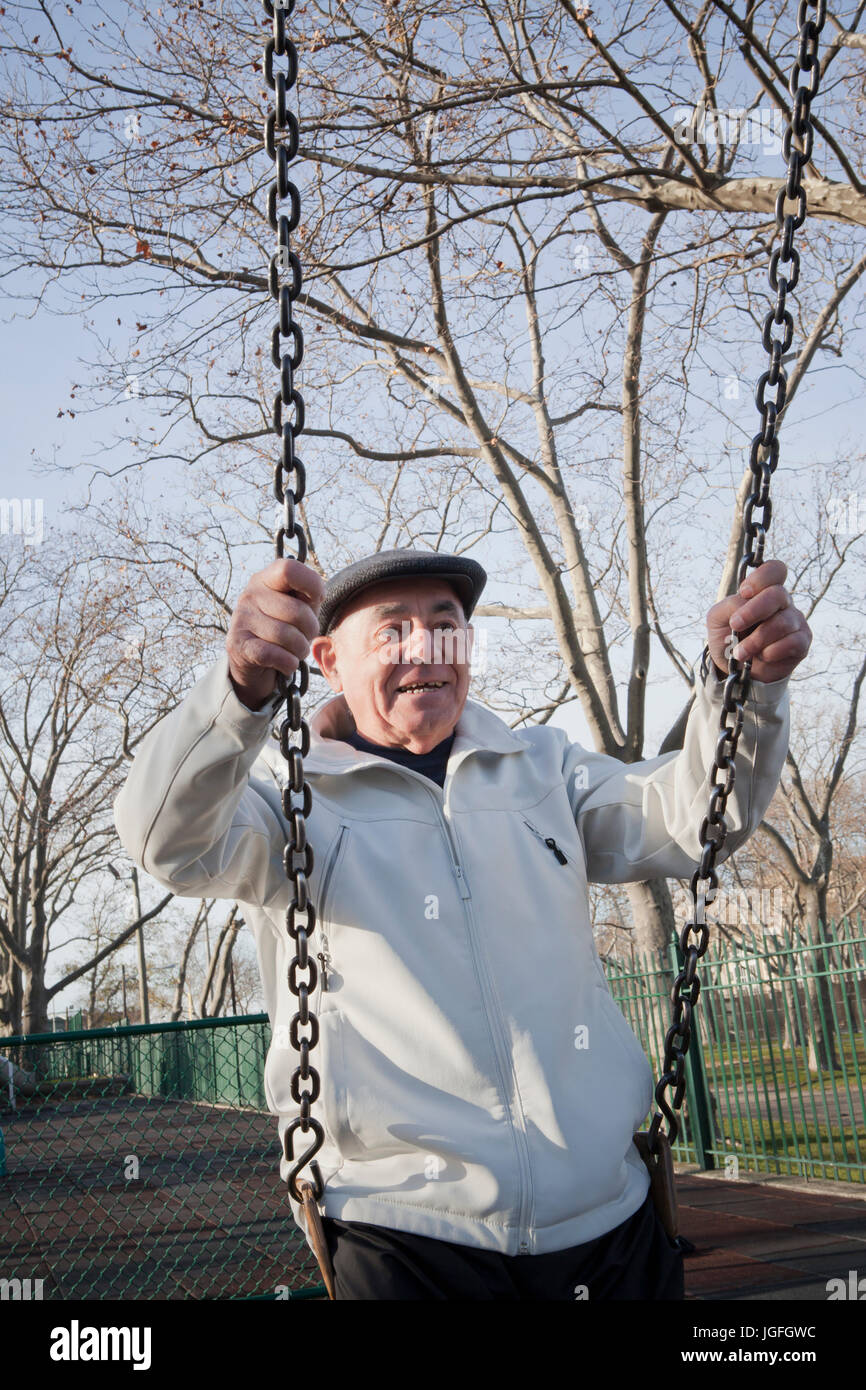 Carefree Hispanic man on swing in park Banque D'Images
