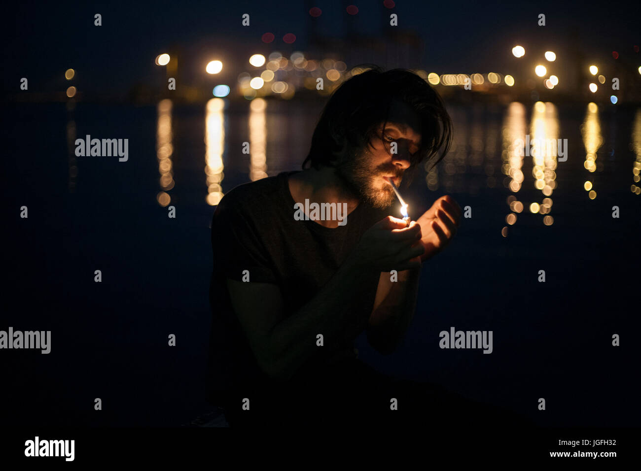 Caucasian man lighting cigarette à Waterfront Banque D'Images
