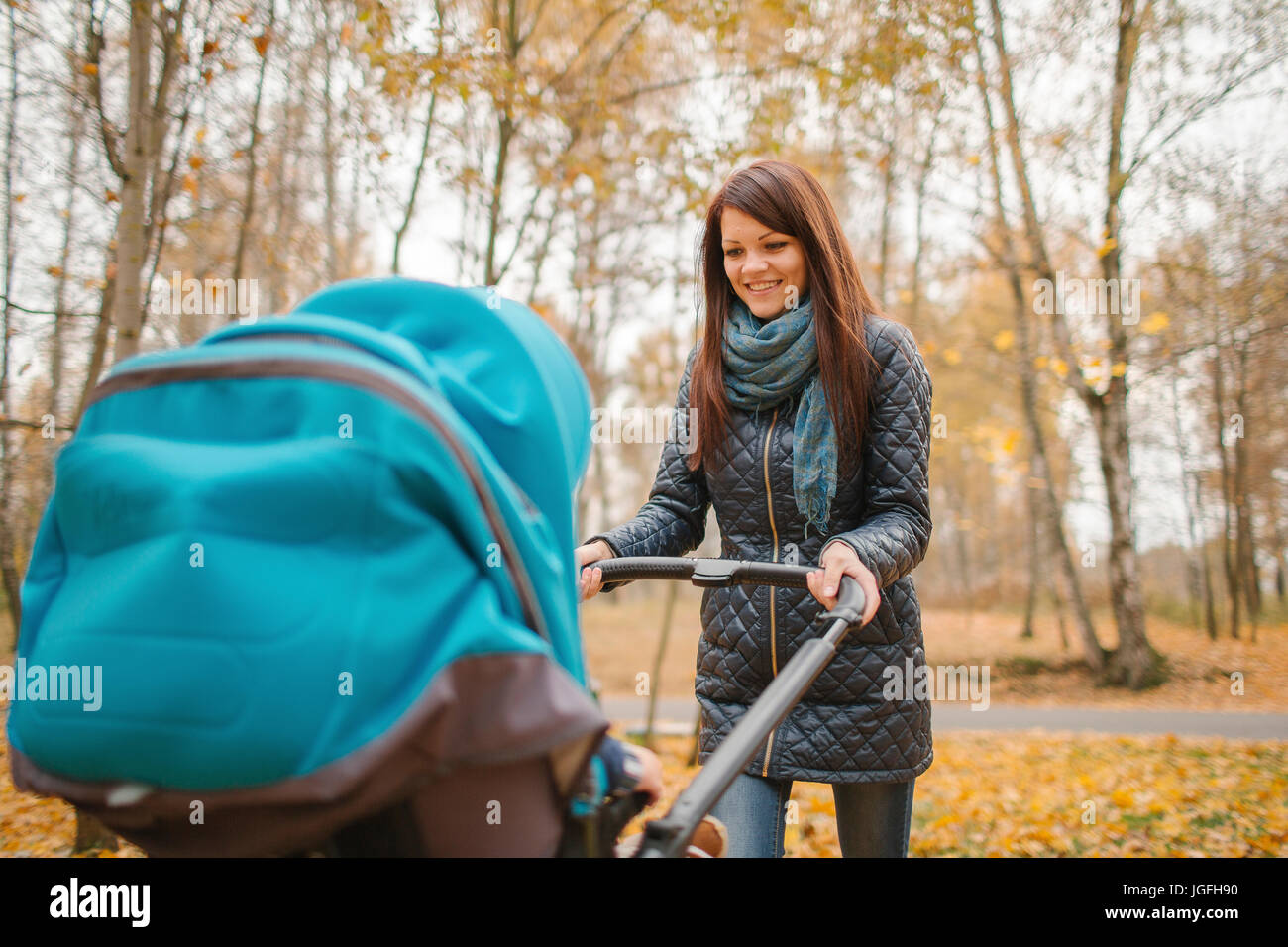 Smiling Middle Eastern woman pushing stroller in park Banque D'Images
