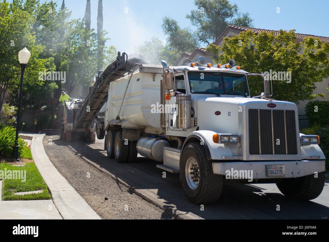 Verse de l'asphalte pulvérisé un convoyeur dans un camion-benne, libérant un nuage de poussière, au cours d'un projet de revêtement routier et de construction dans la région de la baie de San Francisco suburb de San Ramon, Californie, le 26 juin 2017. Banque D'Images