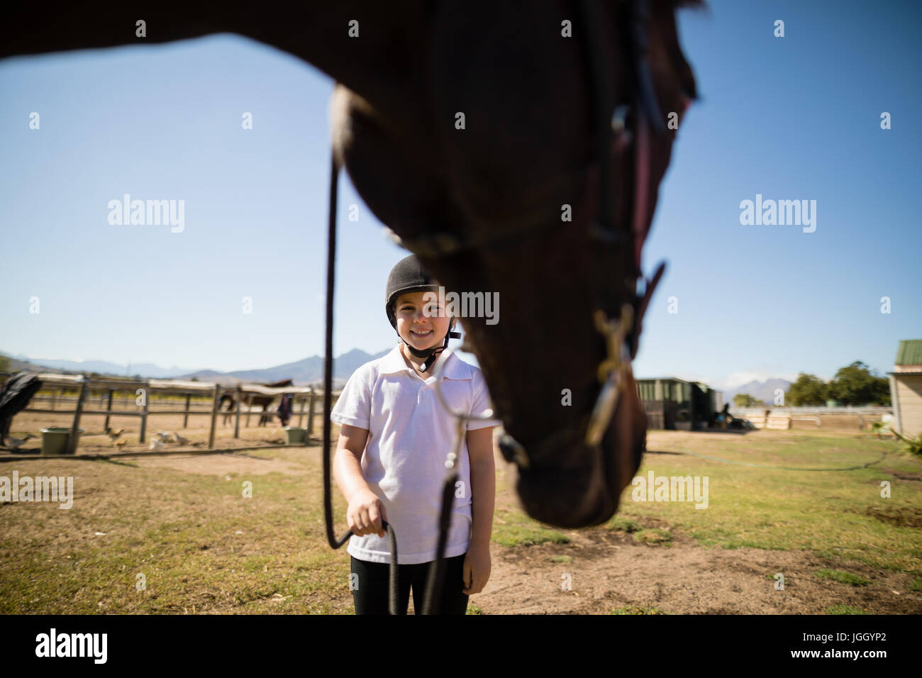 Smiling girl holding le rein du cheval dans le ranch sur une journée ensoleillée Banque D'Images
