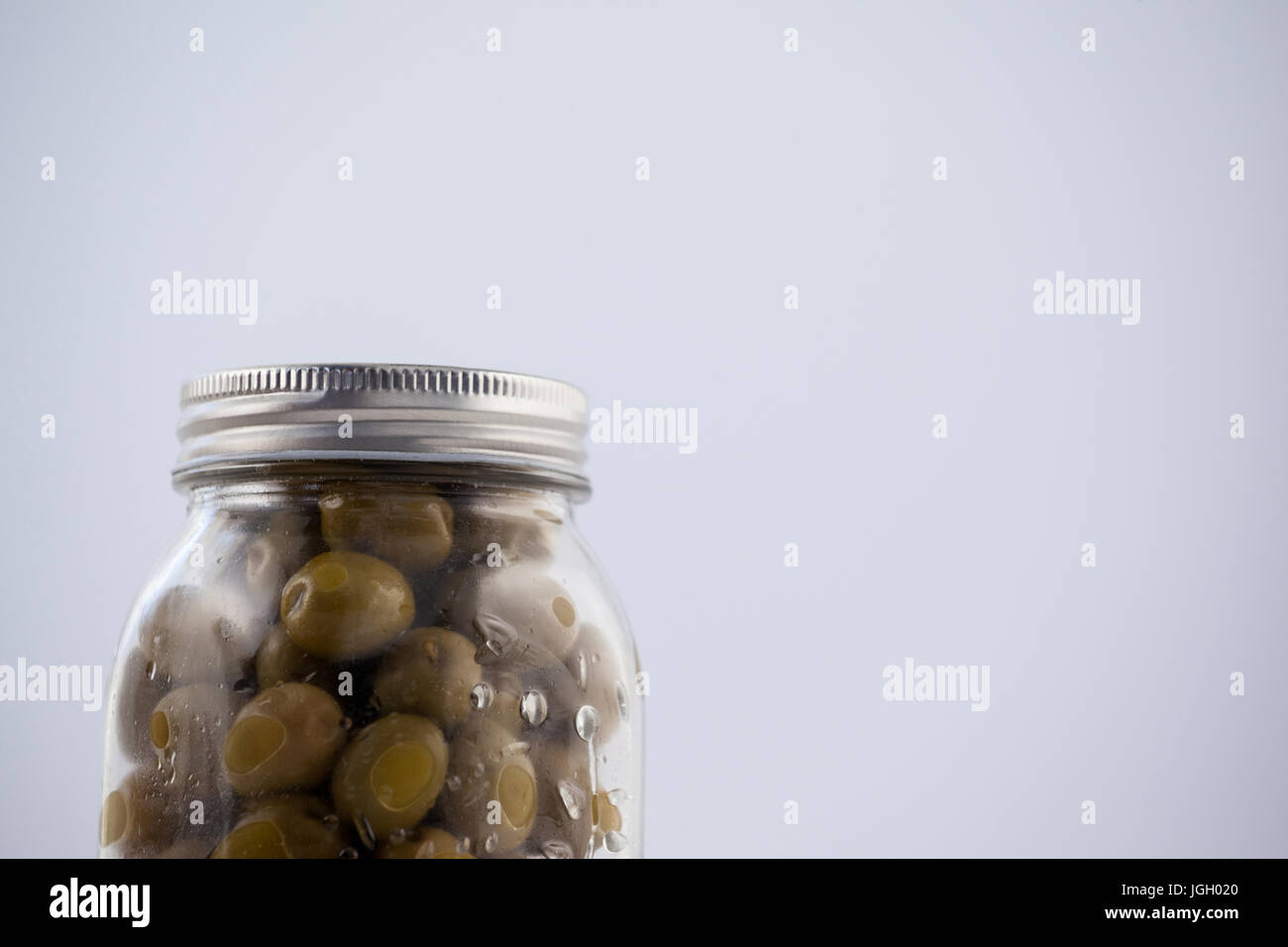 Olive verte dans un bocal en verre avec couvercle d'argent sur la table Banque D'Images